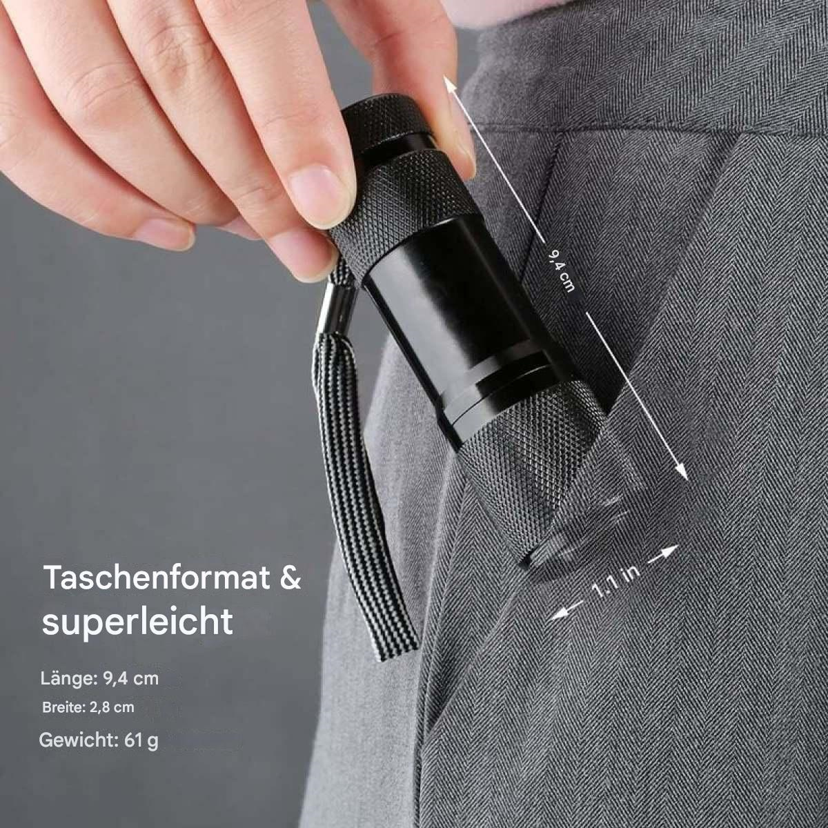 Hand hält eine kleine schwarze Taschenlampe mit Abmessungen und Gewichtsangaben in deutscher Sprache.