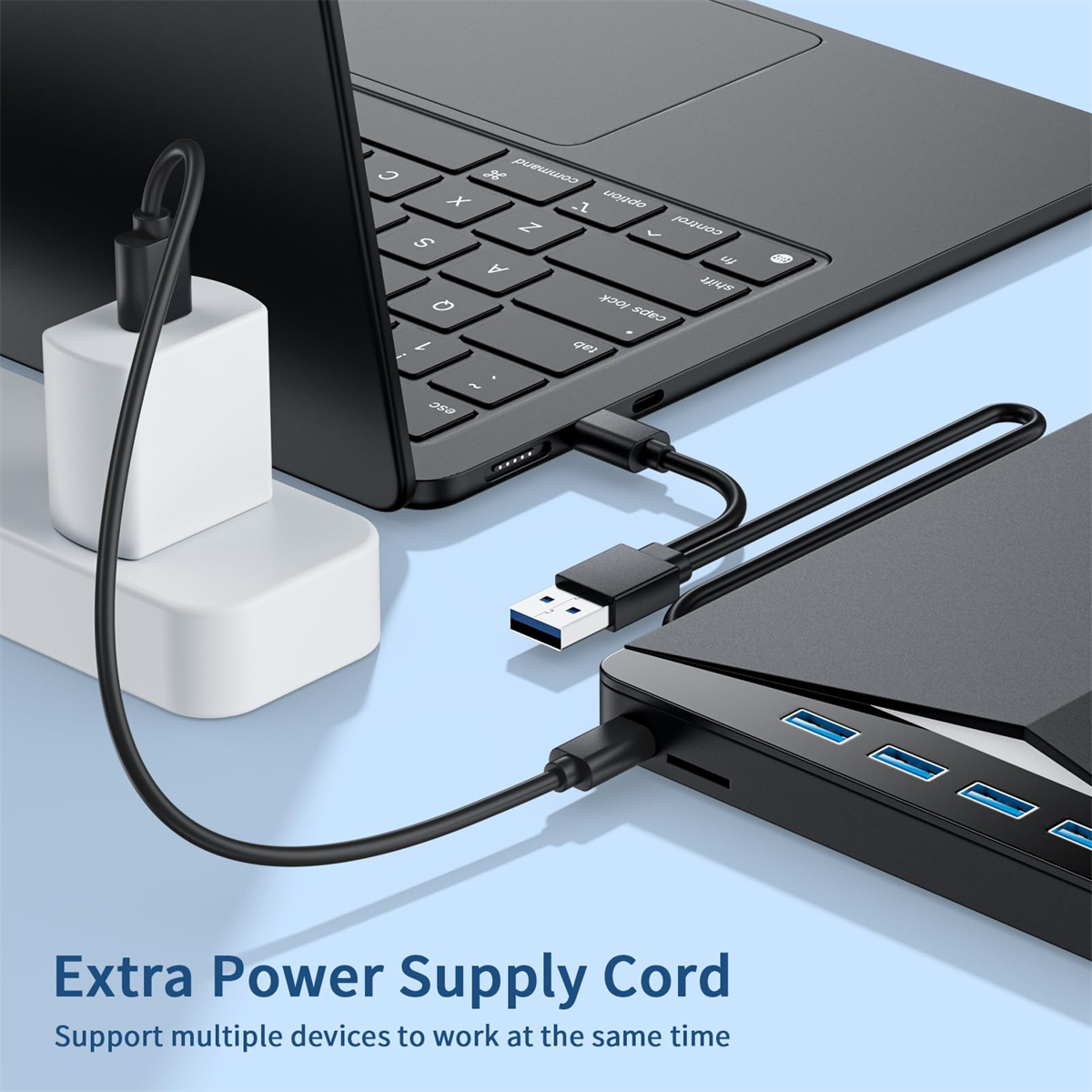 Ein Laptop, der mit einer Stromquelle und einem USB-Hub mit mehreren Anschlüssen verbunden ist.