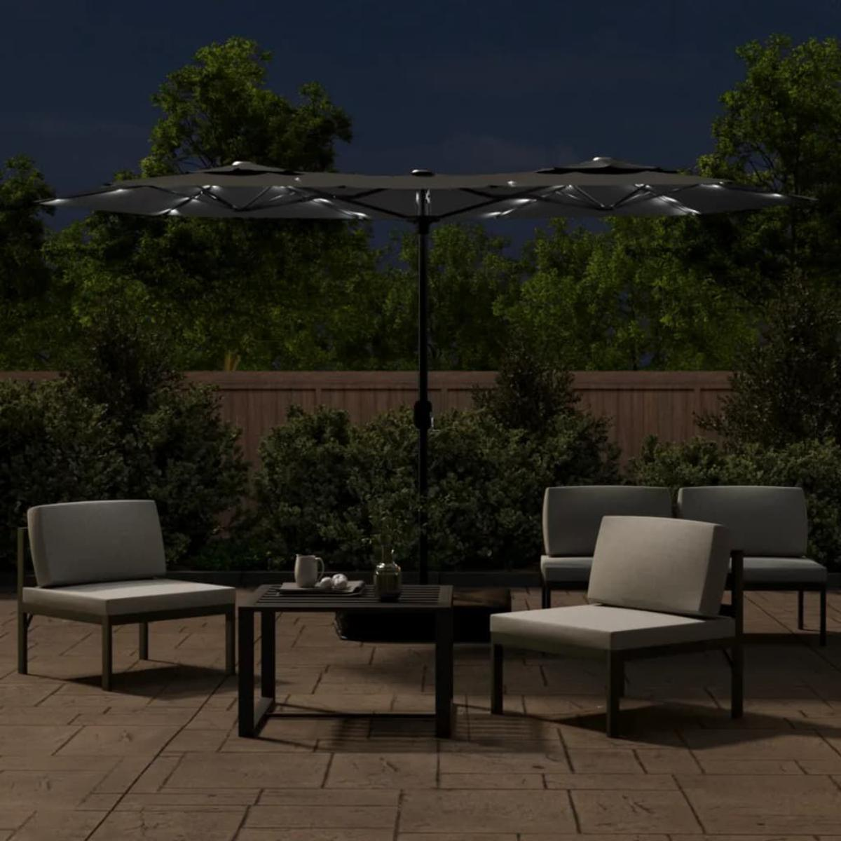 Patio-Setup bei Nacht mit beleuchtetem schwarzem Doppelschirm. Hat Stühle, Tisch und umgebendes Grün.