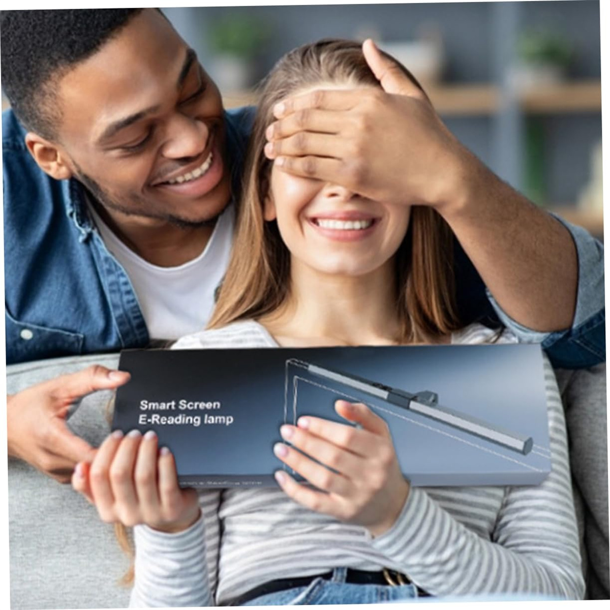 Ein Mann verdeckt die Augen einer Frau, während er eine Geschenkbox präsentiert. Die Box hat eine intelligente Bildschirm-E-Leselampe.