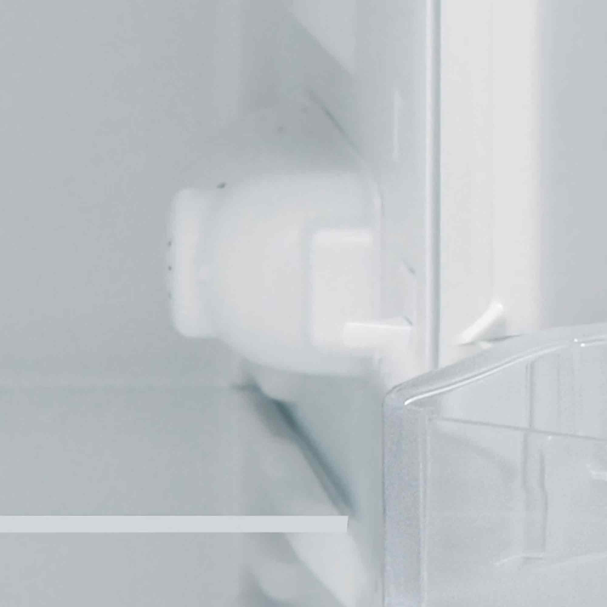 Im Kühlschrank ist ein weißes Kunststoffteil an der Wand befestigt. Der Hintergrund ist weiß.