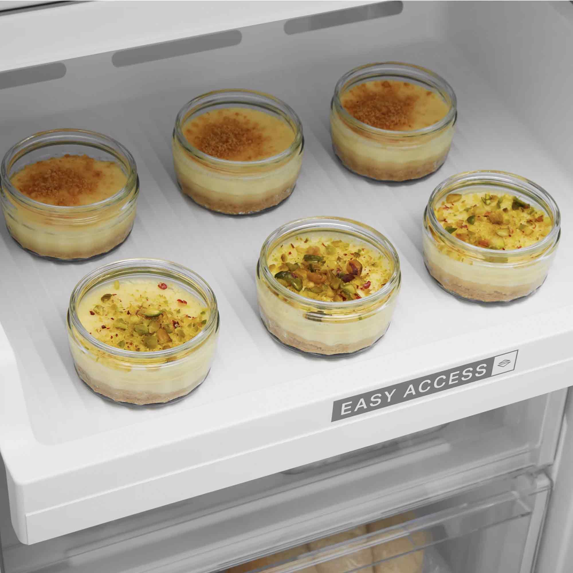 Kühlschrankregal mit sechs kleinen Gläsern Desserts, einige mit Nüssen.