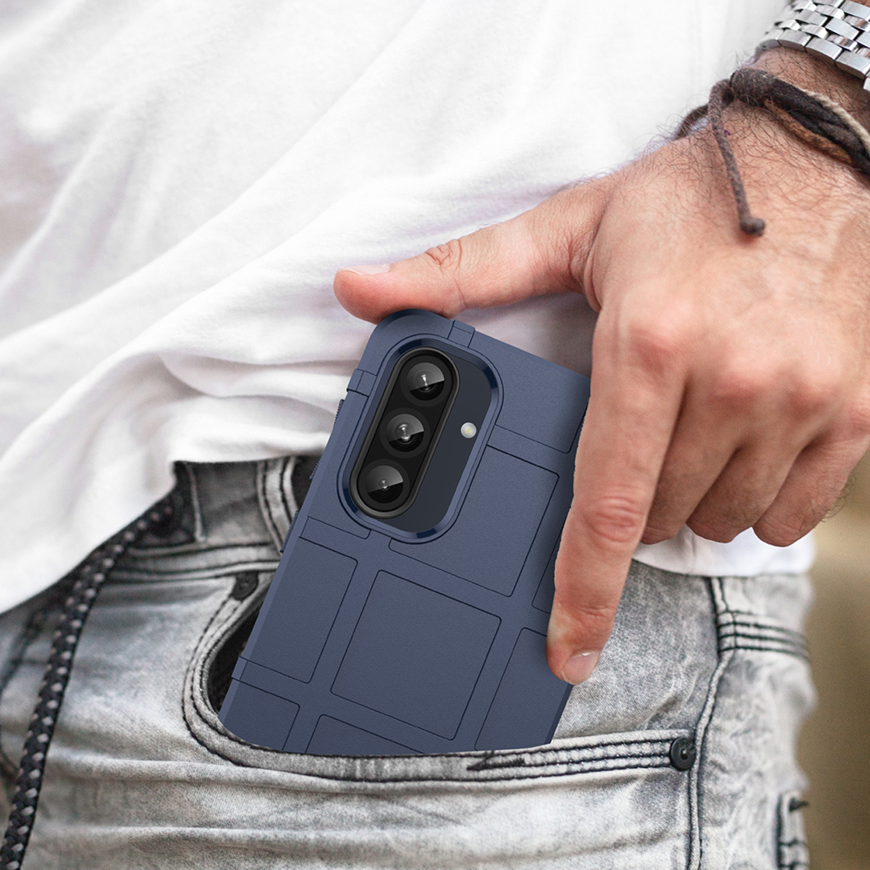 Een persoon houdt een blauwe telefoonhoes in een zak. Draagt een wit overhemd en jeans.