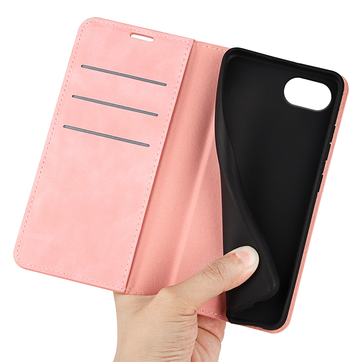 A hand holds a pink phone case, open to reveal a black interior. The phone is absent.