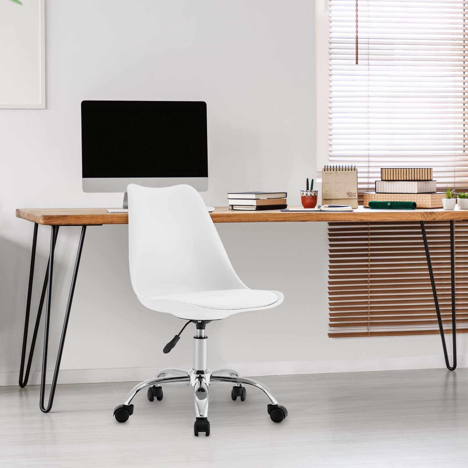Silla blanca en un escritorio de madera con computadora y libros. Ventana con persianas en el fondo.