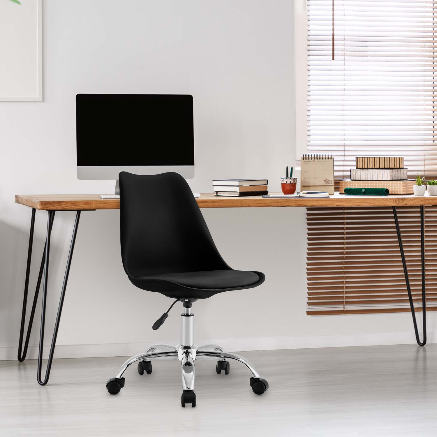 Configuración de oficina. Silla negra en escritorio de madera. Computadora y ventana visibles.