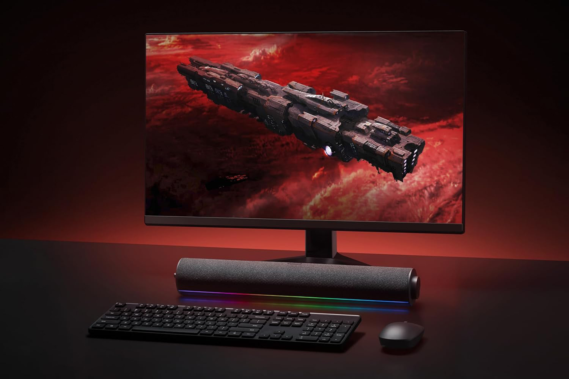 Monitor wyświetlający statek kosmiczny w kosmosie, z klawiaturą i myszą poniżej. Czerwone tło.