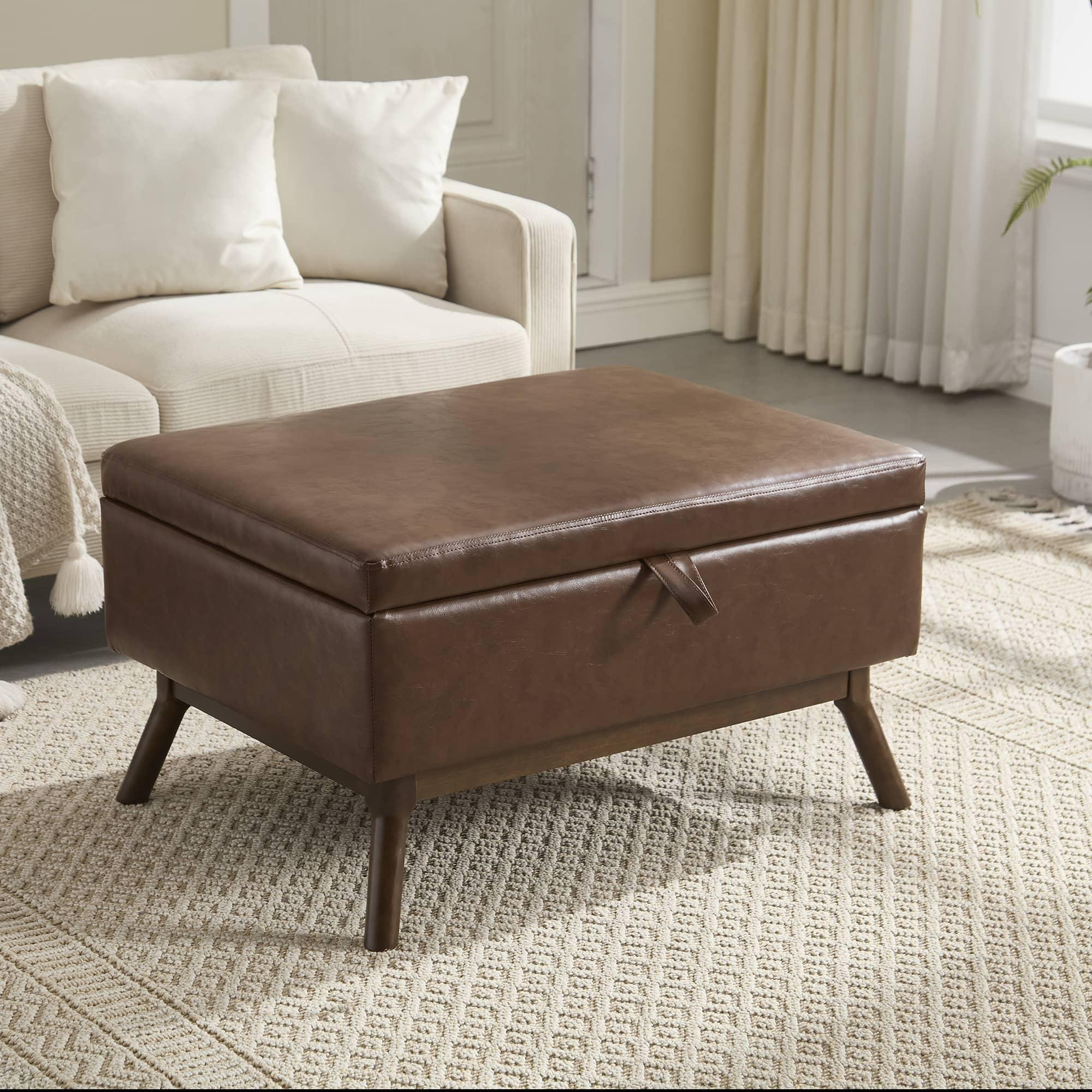 Braune Leder-Ottomane mit einem Staufach. Sie steht auf einem Teppich in der Nähe einer Couch.
