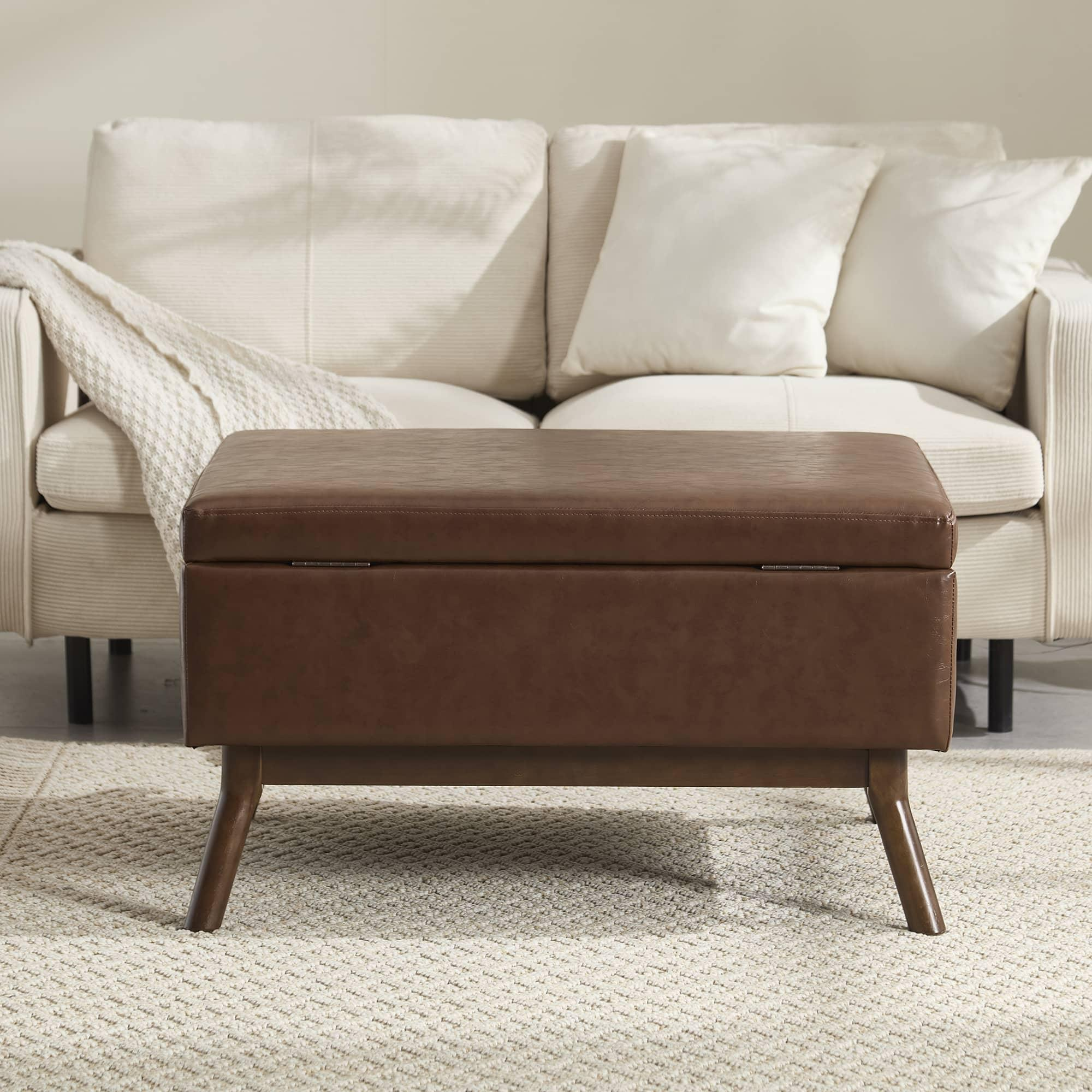 Braune Leder-Ottomane mit Staufach, in der Nähe eines weißen Sofas und Kissen.