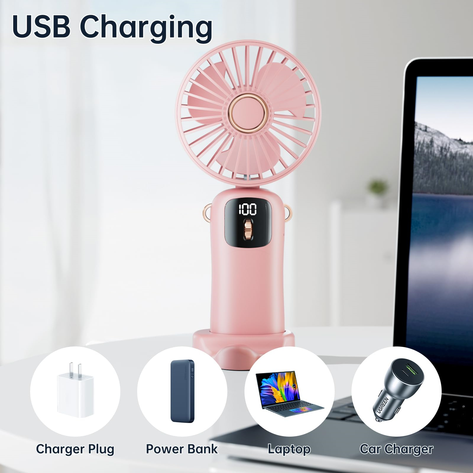 Rosa Ventilator mit Zubehör: Ladegerät, Powerbank, Laptop und Autoladegerät, alles auf einem Tisch.