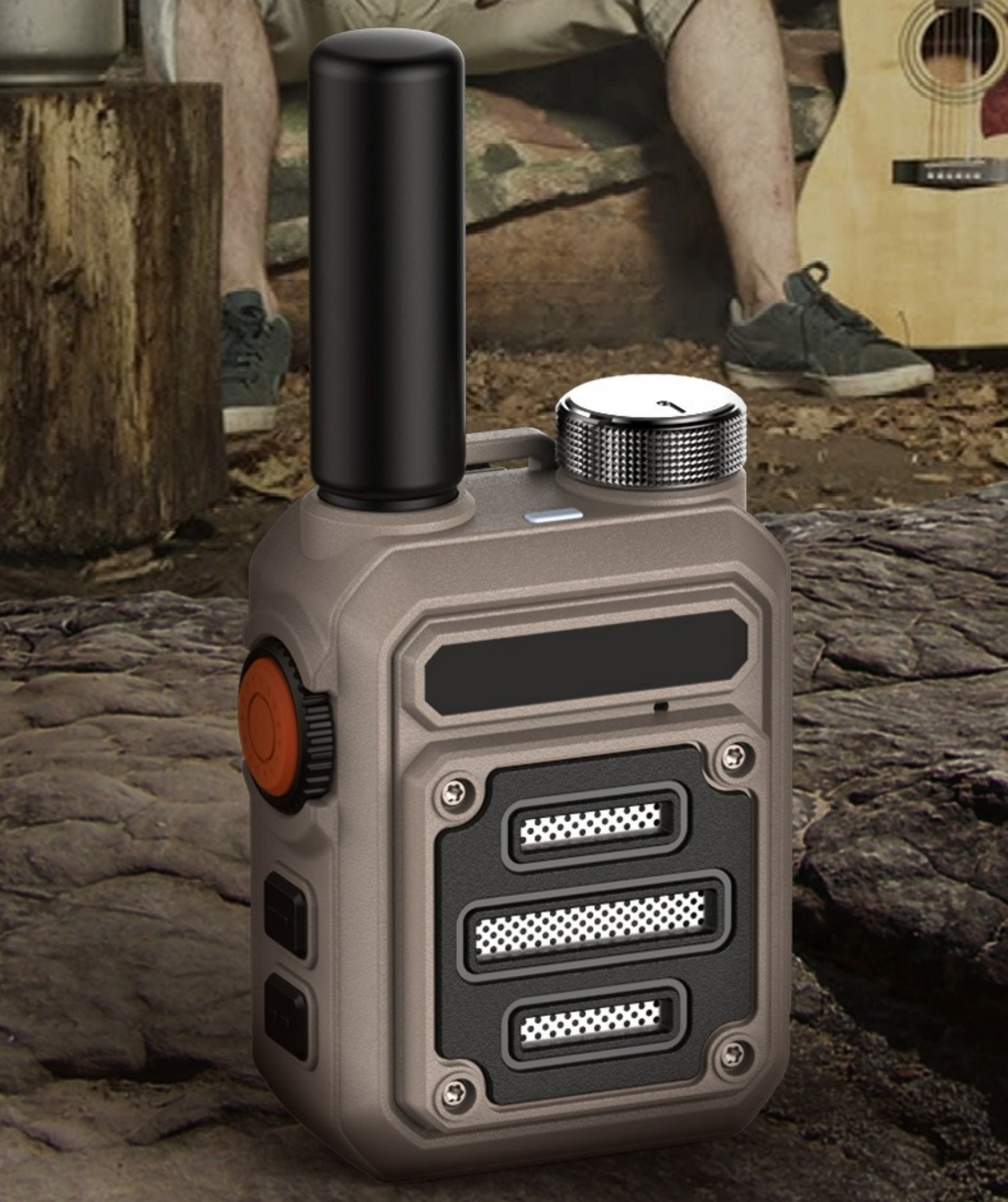 Ein Funkgerät. Es ist braun und grau. Eine Person mit Gitarre im Hintergrund.