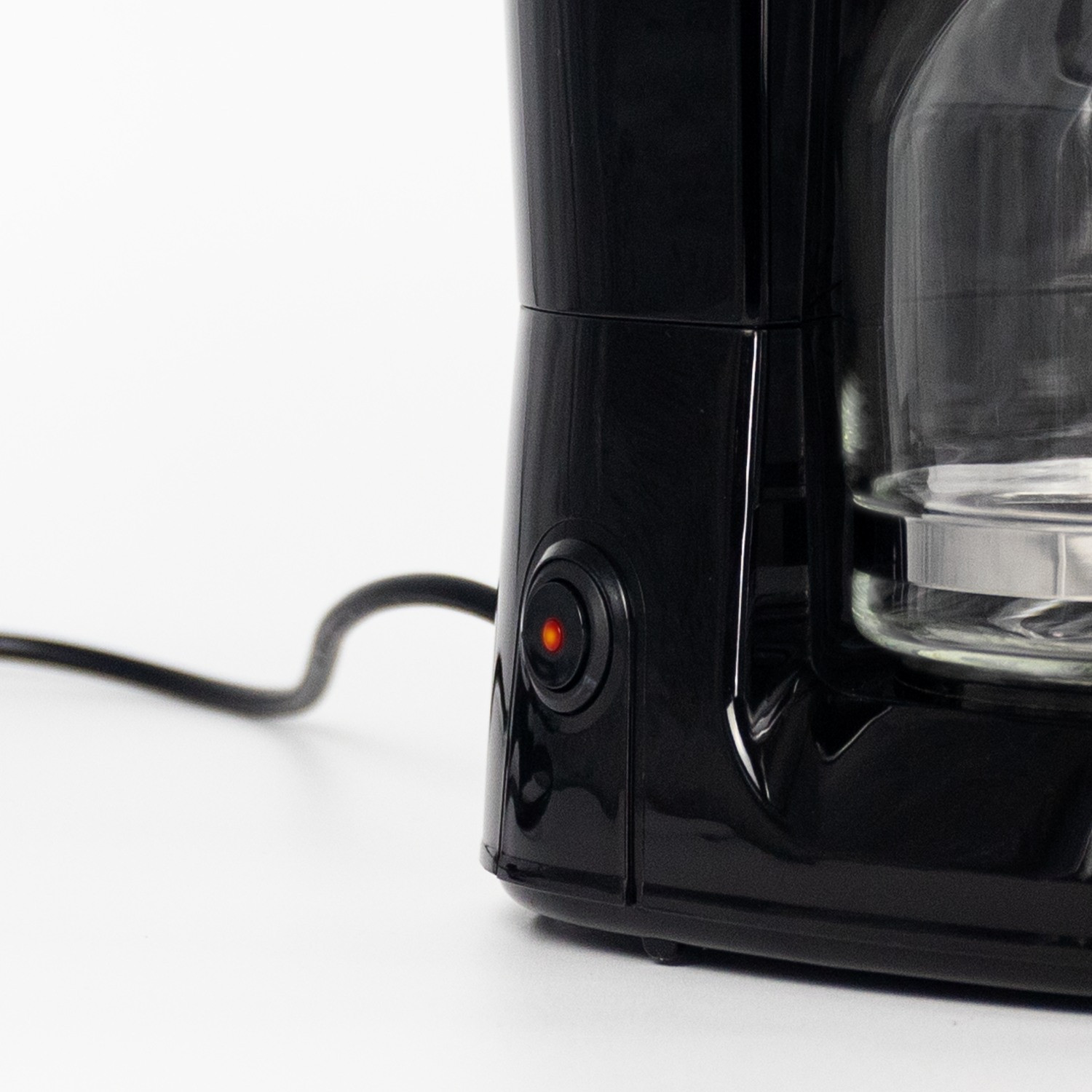 Primer plano de una cafetera negra con un botón de encendido rojo.
