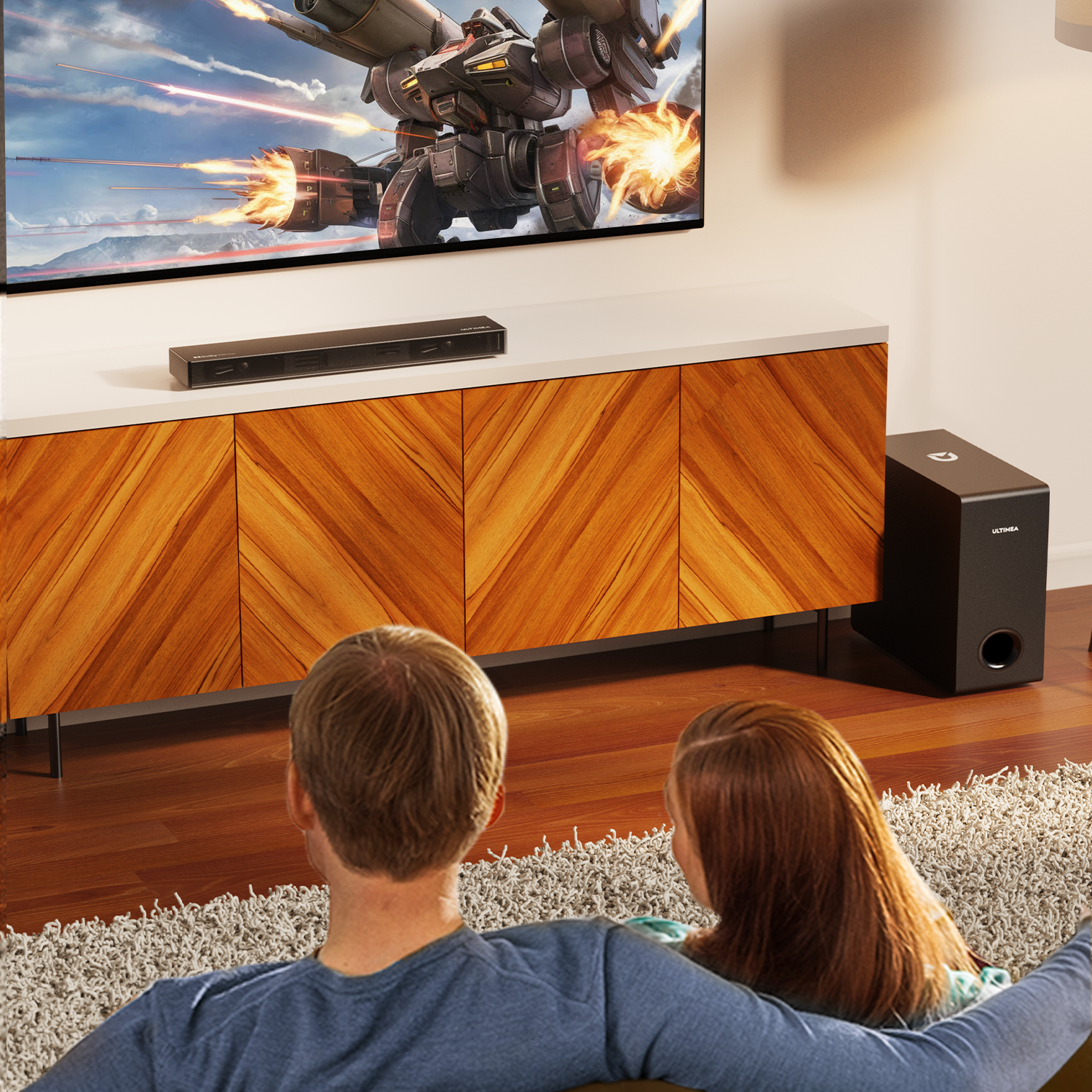 Paar sieht fern mit Soundbar und Subwoofer. Der Fernseher zeigt eine futuristische Szene. Holzschrank und Teppich sind im Raum.