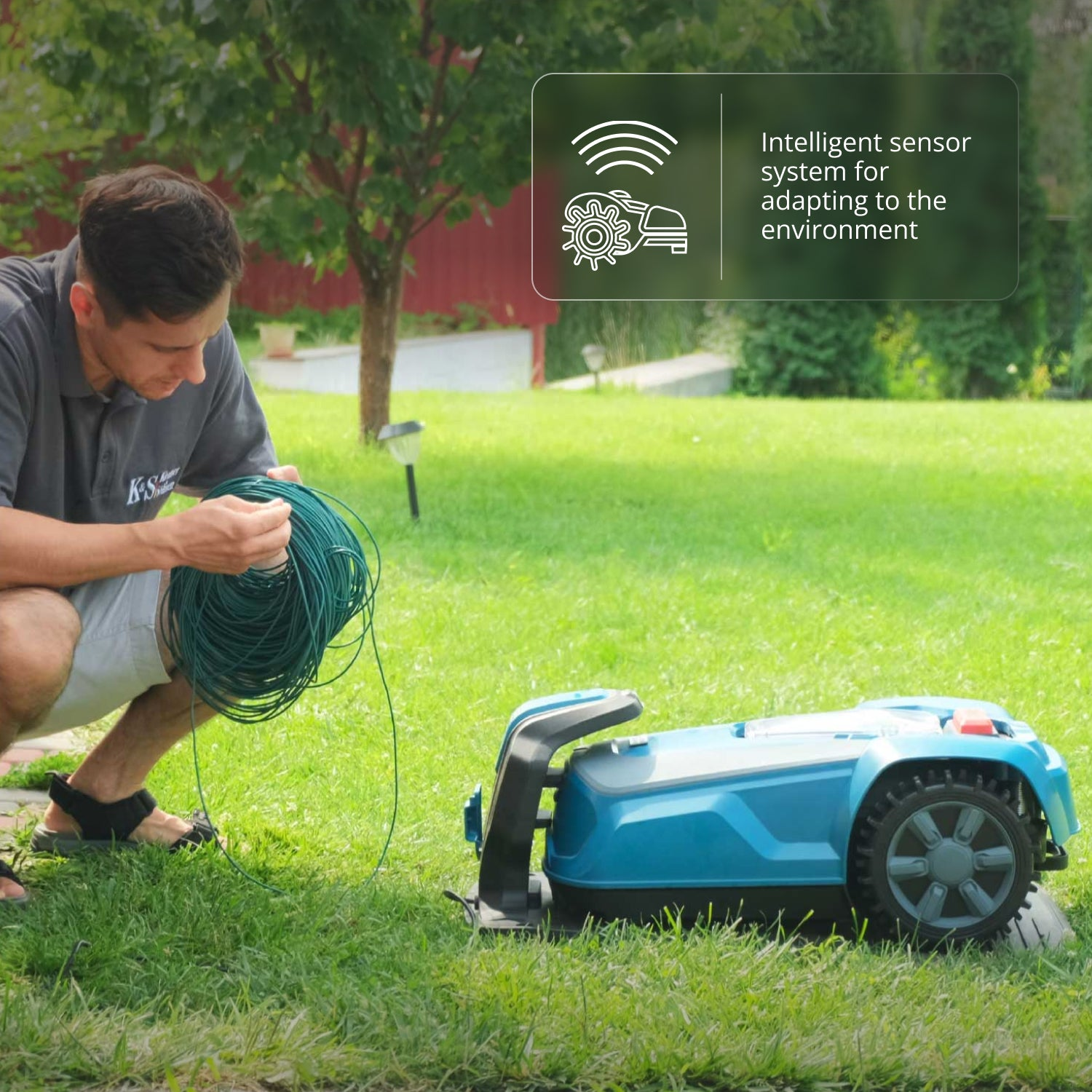 Hombre con cable, cortacésped robótico sobre hierba. Árbol y fondo verde. Sistema de sensor inteligente.