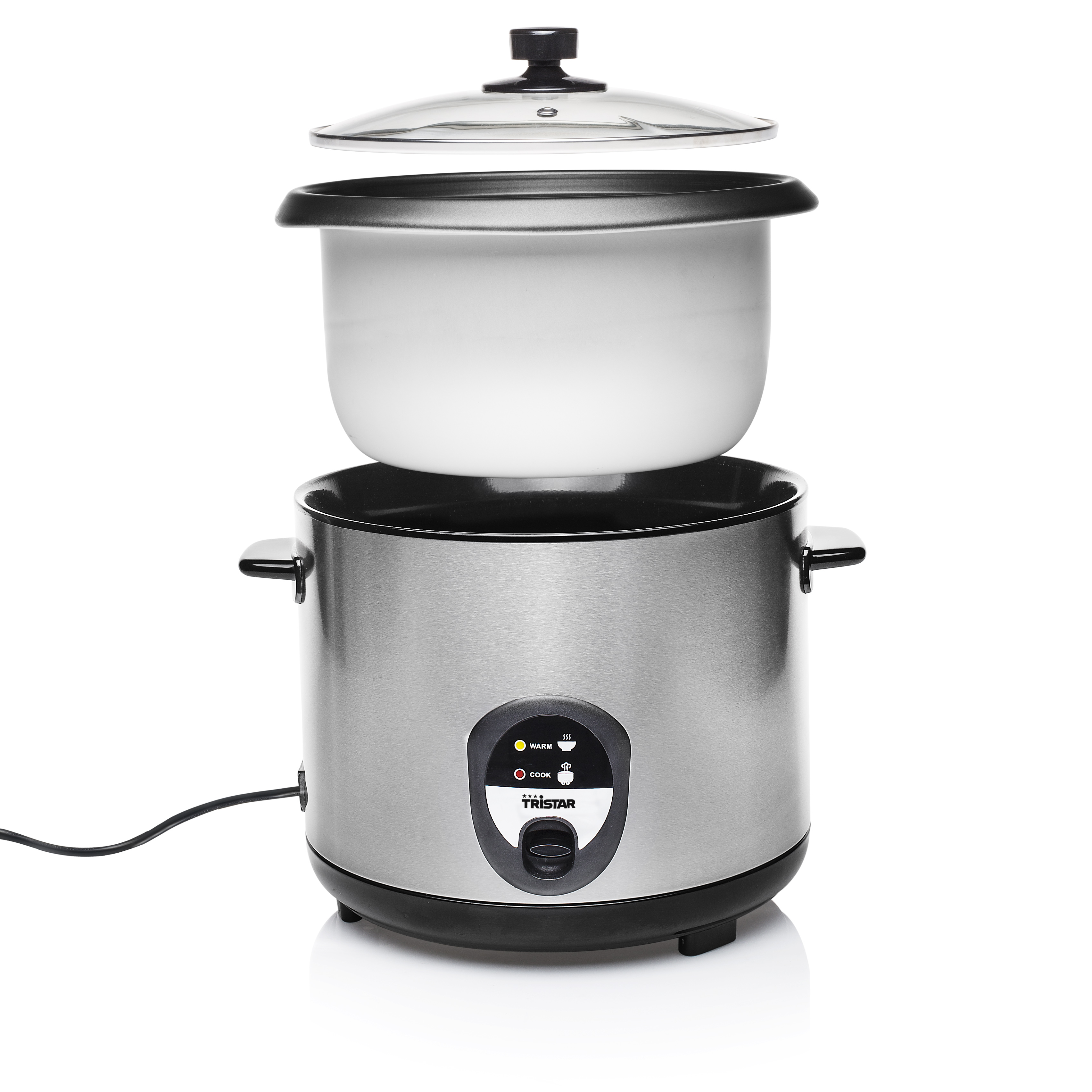 Una cuociriso con riso giallo e un cucchiaio è appoggiata su un bancone. Vicino ci sono una pianta, un coltello e un asciugamano.