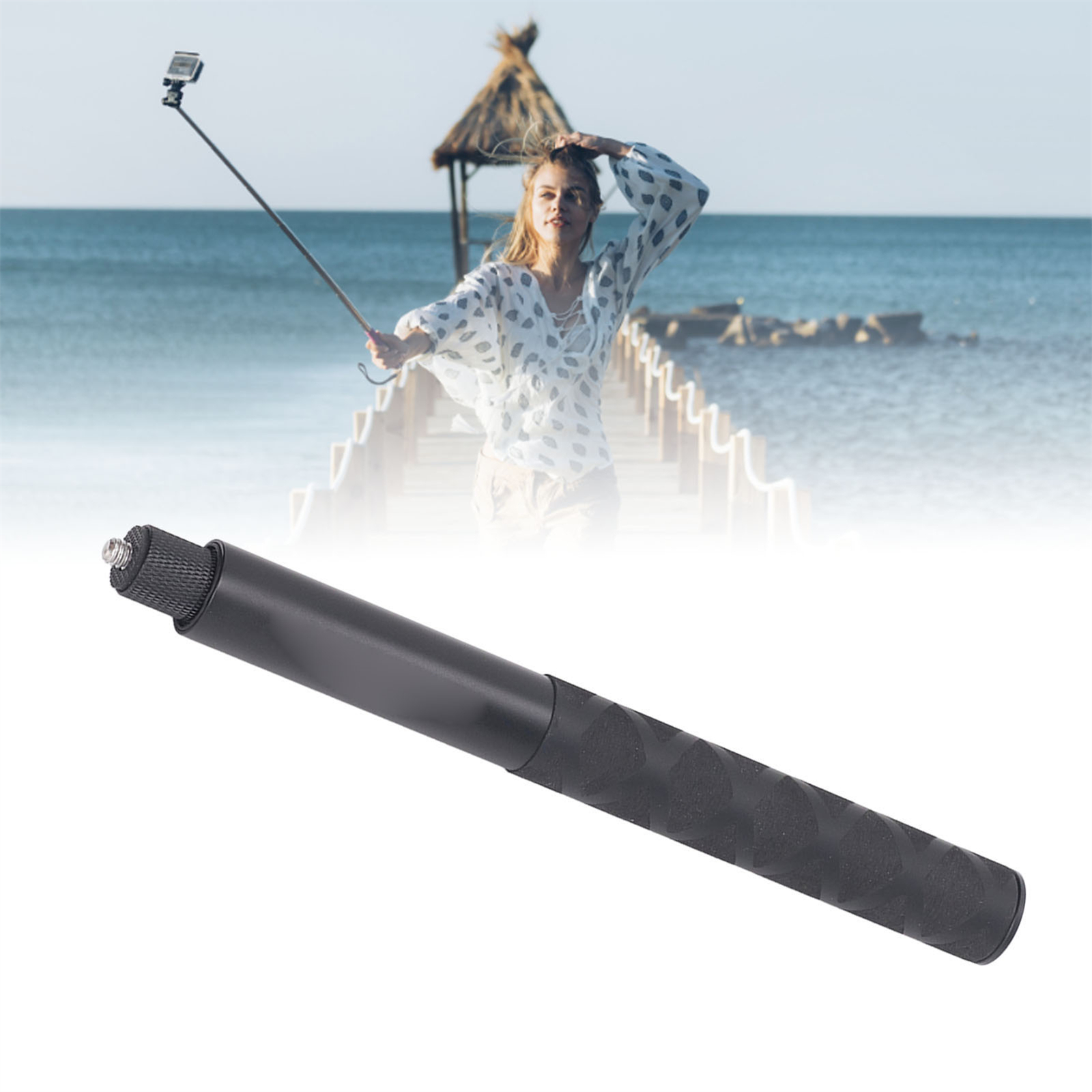 Eine Person hält einen Selfie-Stick mit angeschlossenem Telefon auf einem Holzsteg mit Strand im Hintergrund.