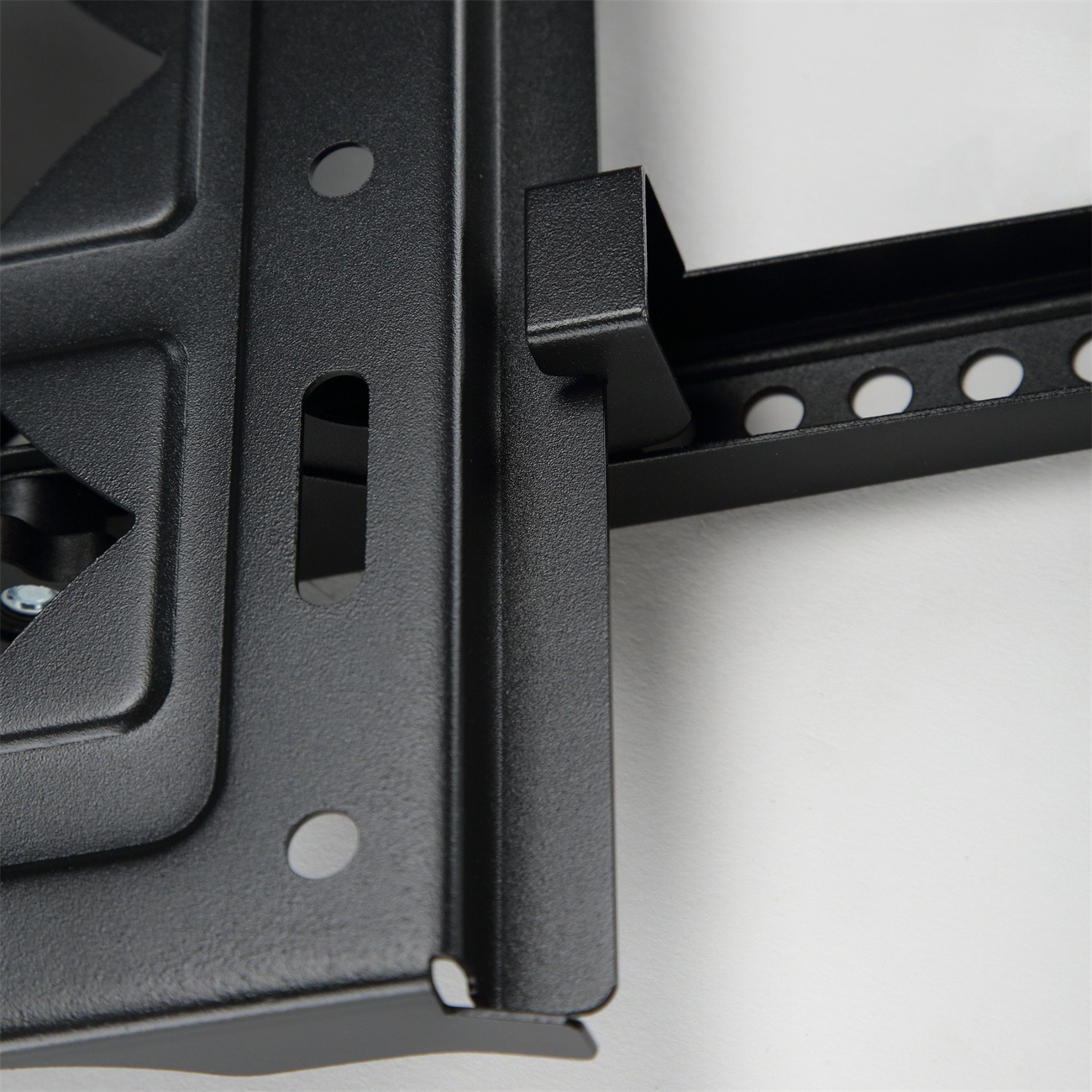 Eine schwarze TV-Wandhalterung aus Metall, mit einer weißen Wand dahinter.