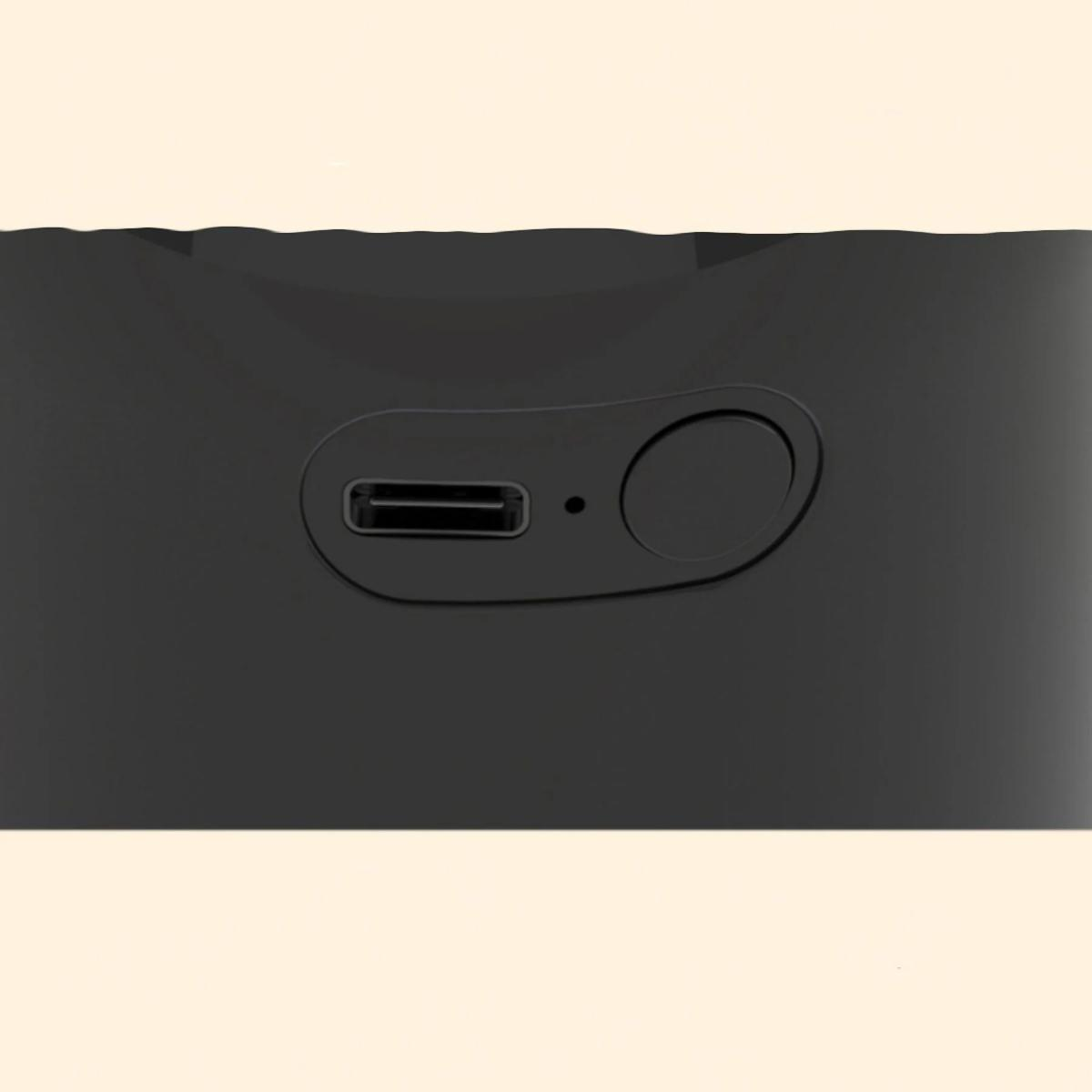 Nahaufnahme eines schwarzen Geräts mit USB-Anschluss und Knopf, vor hellbeigem Hintergrund.