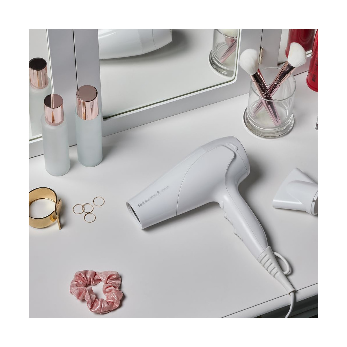 Ein weißer Haartrockner neben Schönheitsprodukten und Accessoires auf einem weißen Schminktisch.