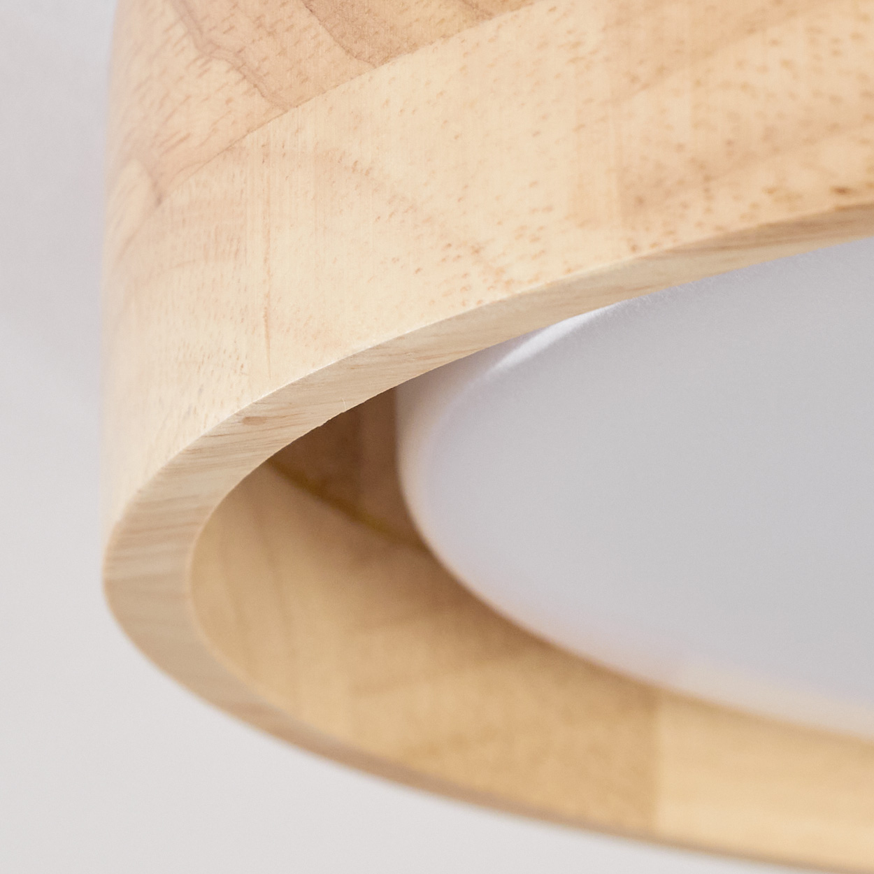 Nahaufnahme einer Deckenlampe aus Holz. Die Lampe hat einen Holzrahmen und eine weiße, opake Mitte.