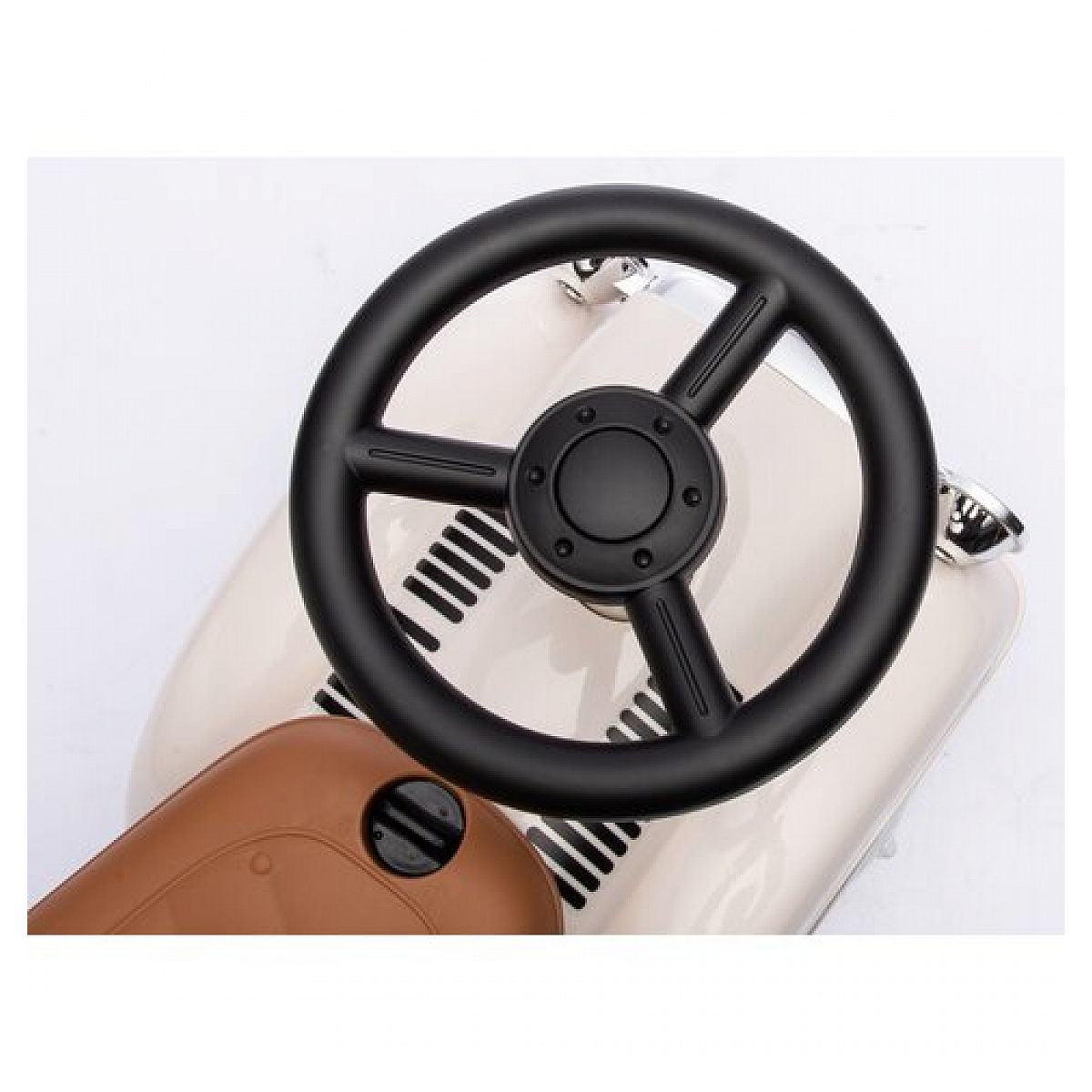 Czarna kierownica na kremowym samochodzie zabawce. Białe tło.