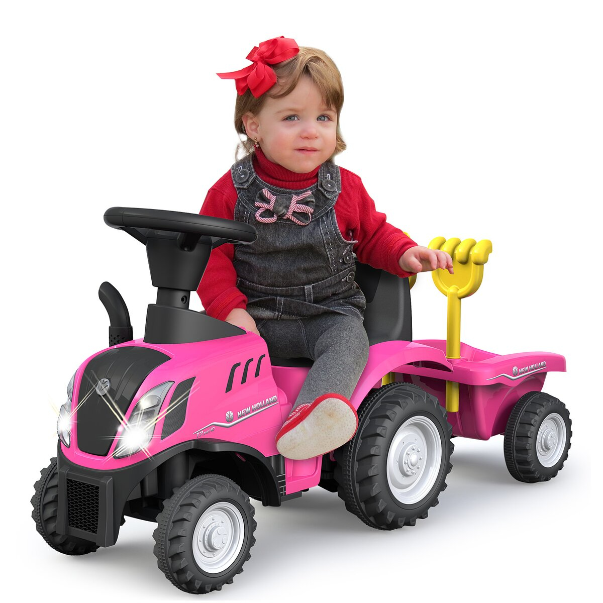 Un niño pequeño sentado en un tractor rosa con un lazo rojo. El tractor tiene un remolque.