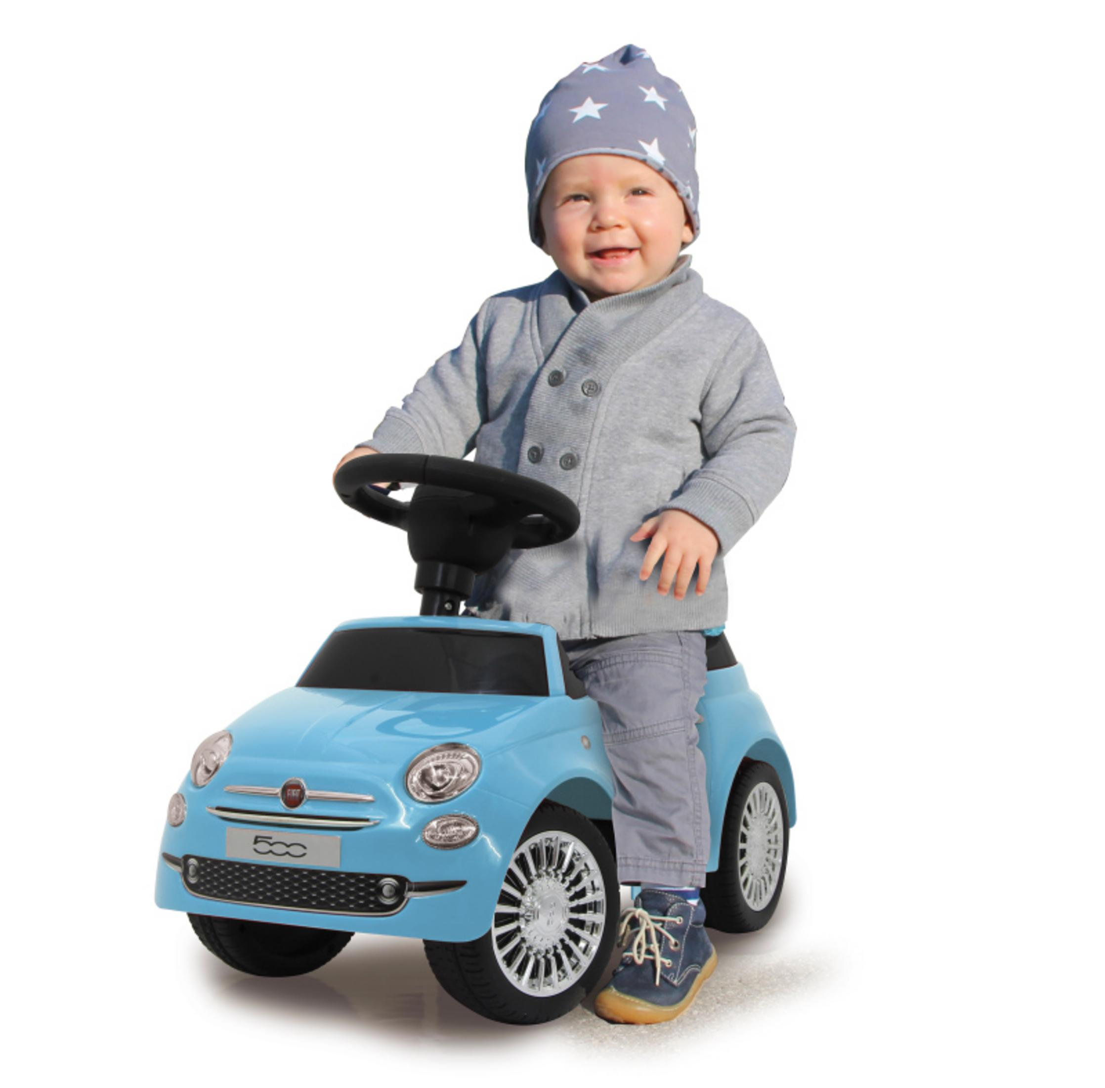 Niemowlę siedzi w jasnoniebieskim samochodziku. Niemowlę ma na sobie czapkę i szary sweter.