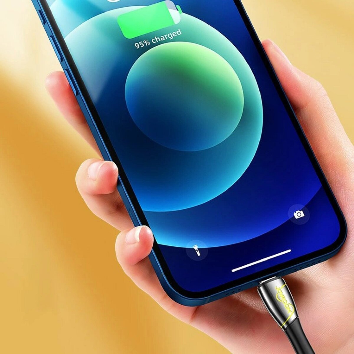 Eine Hand, die ein blaues Telefon hält, mit einem eingesteckten Ladekabel.