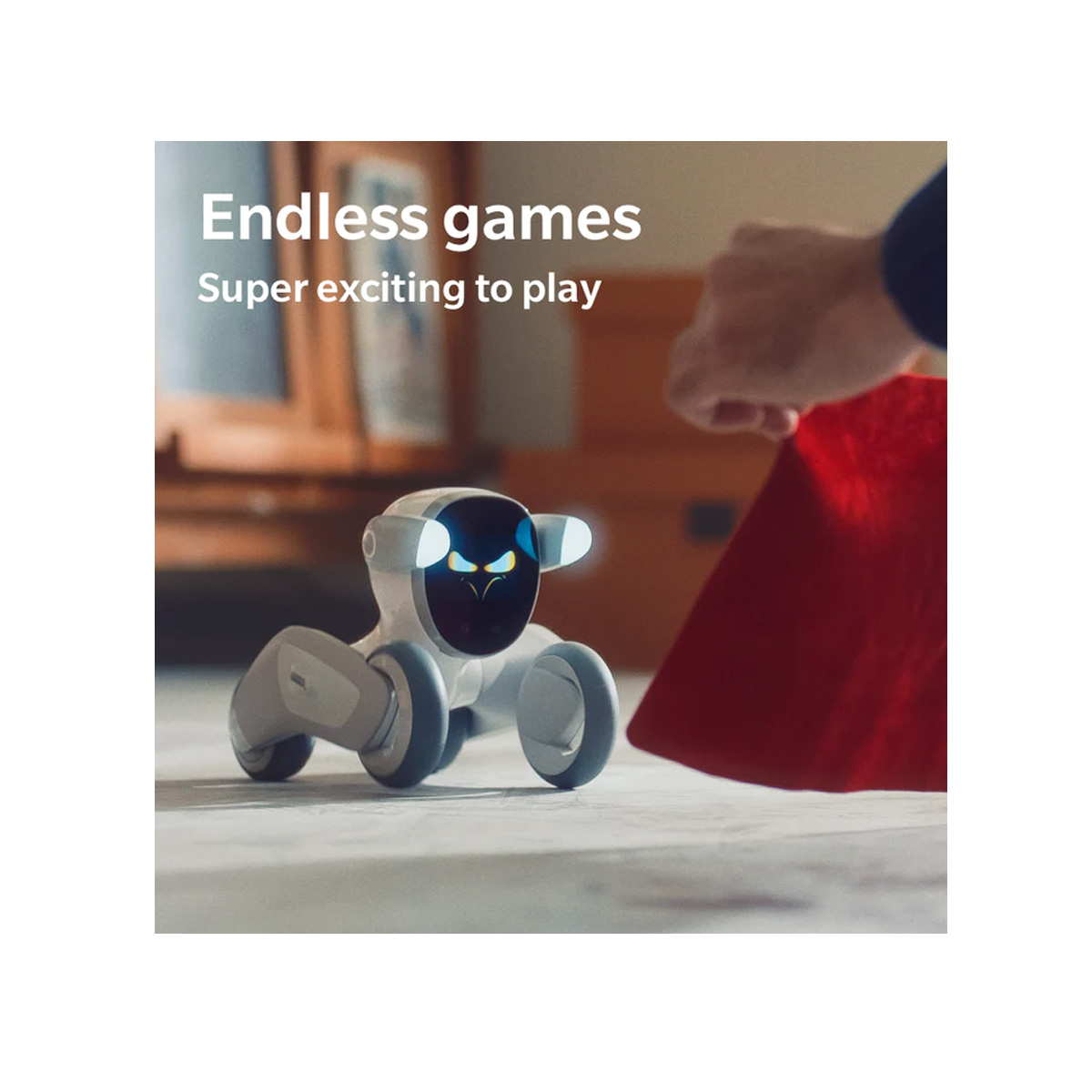 Yüzeyde beyaz bir robot oyuncağı. Bir kişi arka planda kırmızı bir nesne tutuyor.