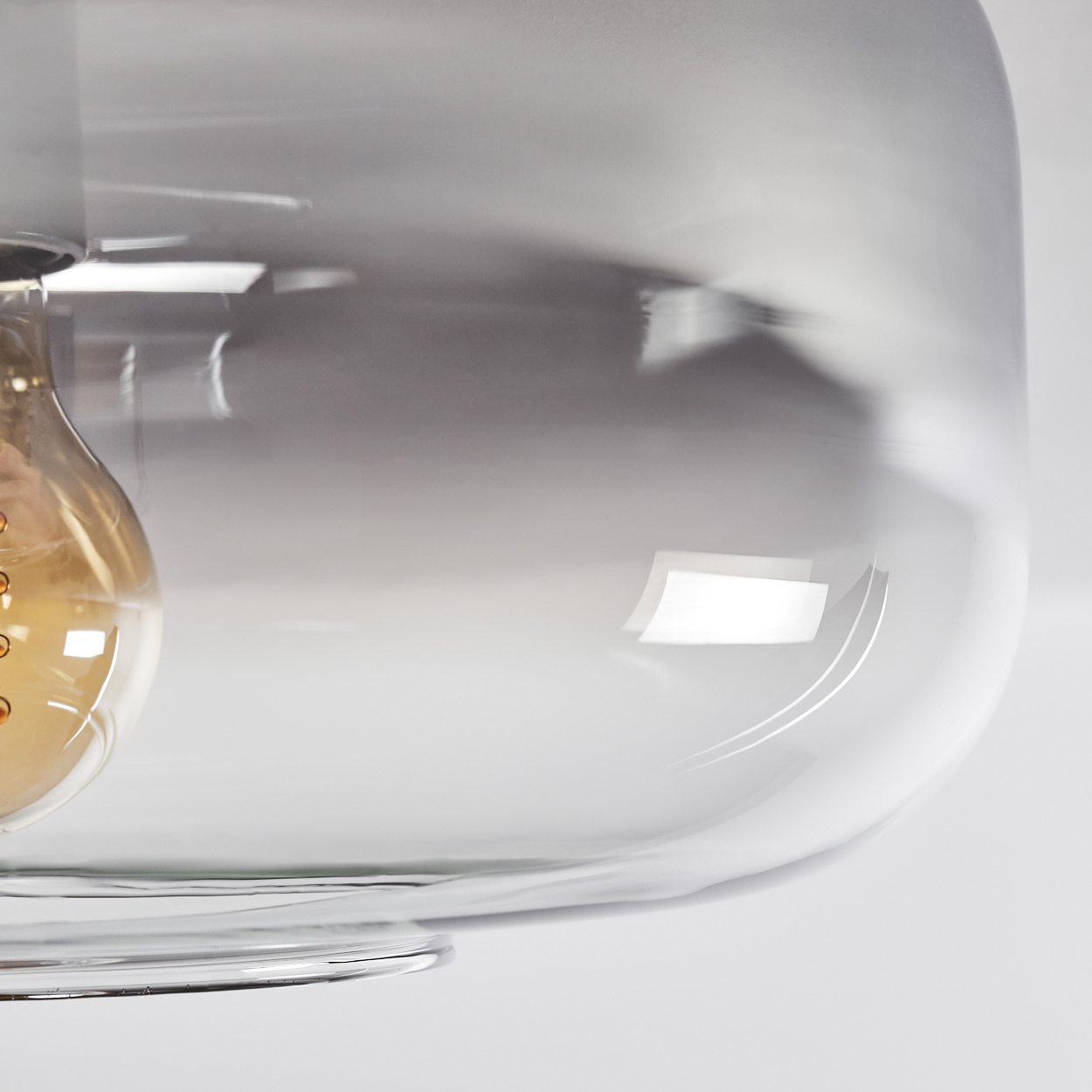 Nahaufnahme einer Deckenleuchte, die einen transparenten Glasschirm mit sichtbarer Glühbirne zeigt.
