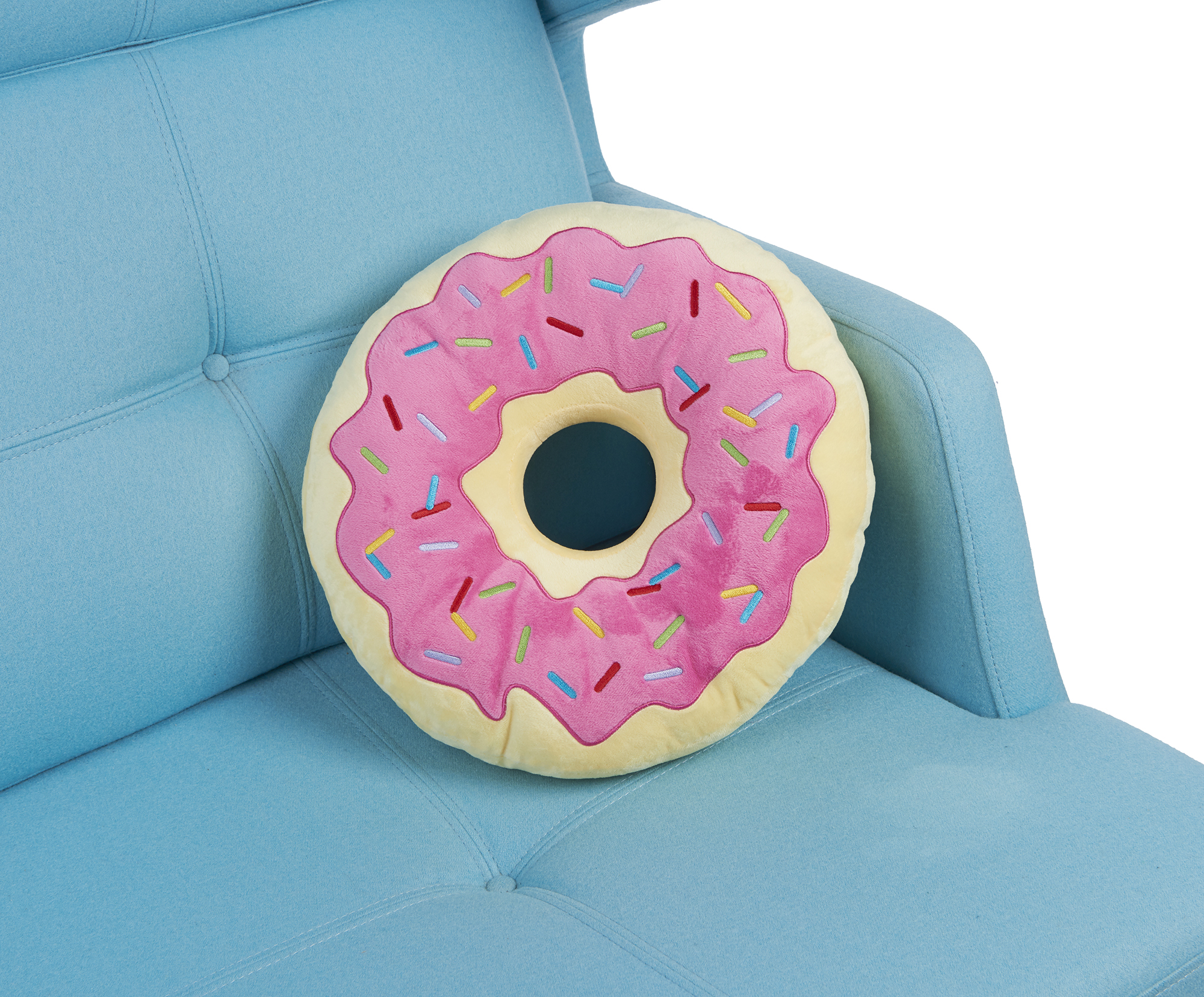 Ein Kissen in Donutform mit rosa Zuckerguss und Streuseln liegt auf einem blauen Sofa.