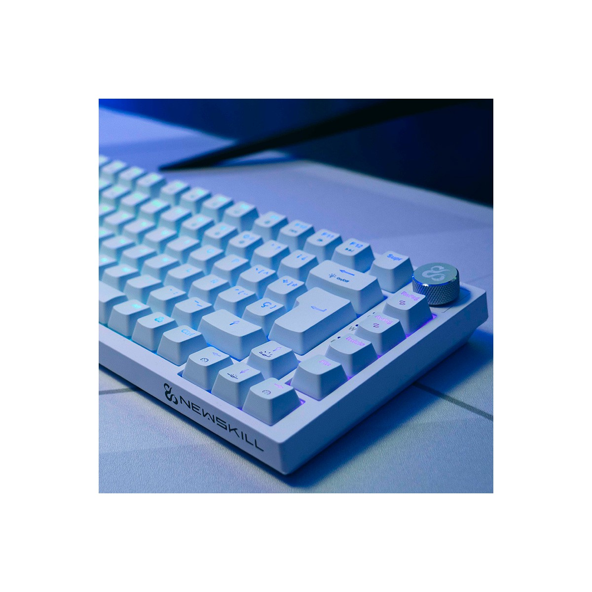 Primer plano de un teclado blanco con teclas iluminadas. Logotipo de Newskill en el teclado. El fondo es una superficie gris clara borrosa.