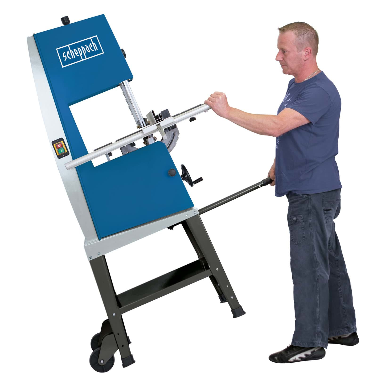Man die een blauw-grijze lintzaag gebruikt, aan de hendel trekt, in een werkplaats.