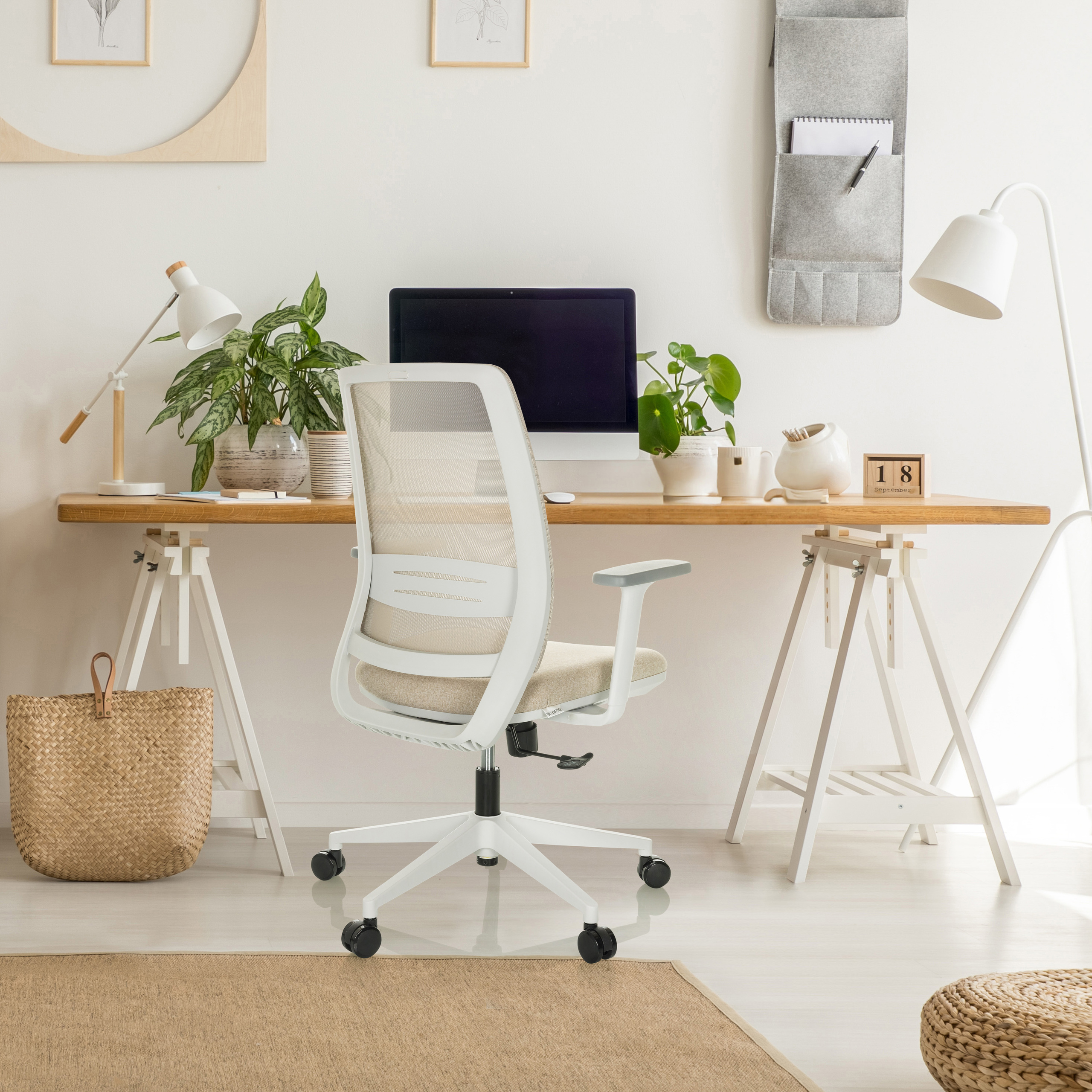 Büro mit weißem Stuhl, Holztisch, Pflanzen und einem Weidenkorb.