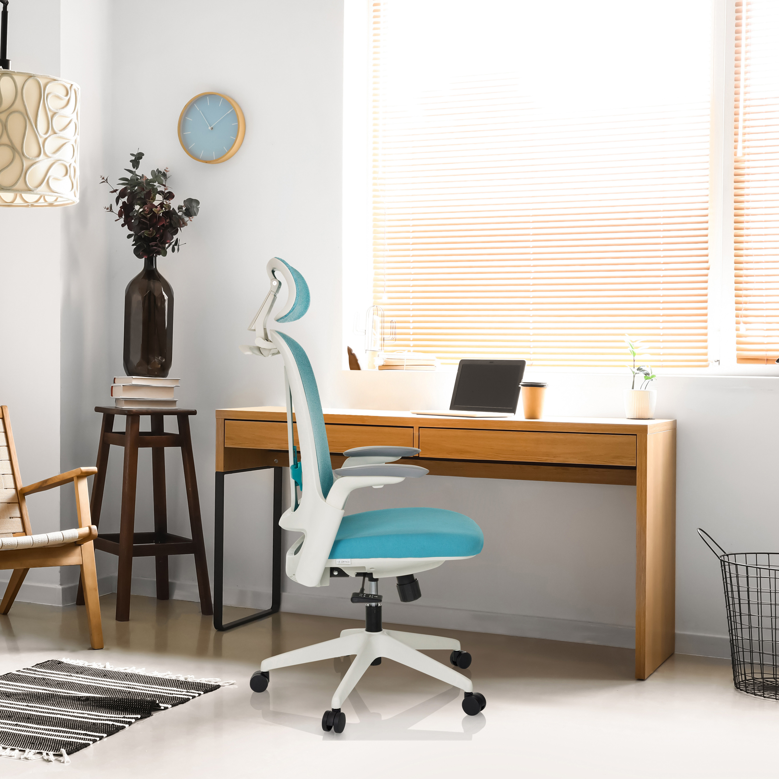Ein helles Büro mit blau-weißem Stuhl, Schreibtisch, Laptop, Fenster und Zubehör.