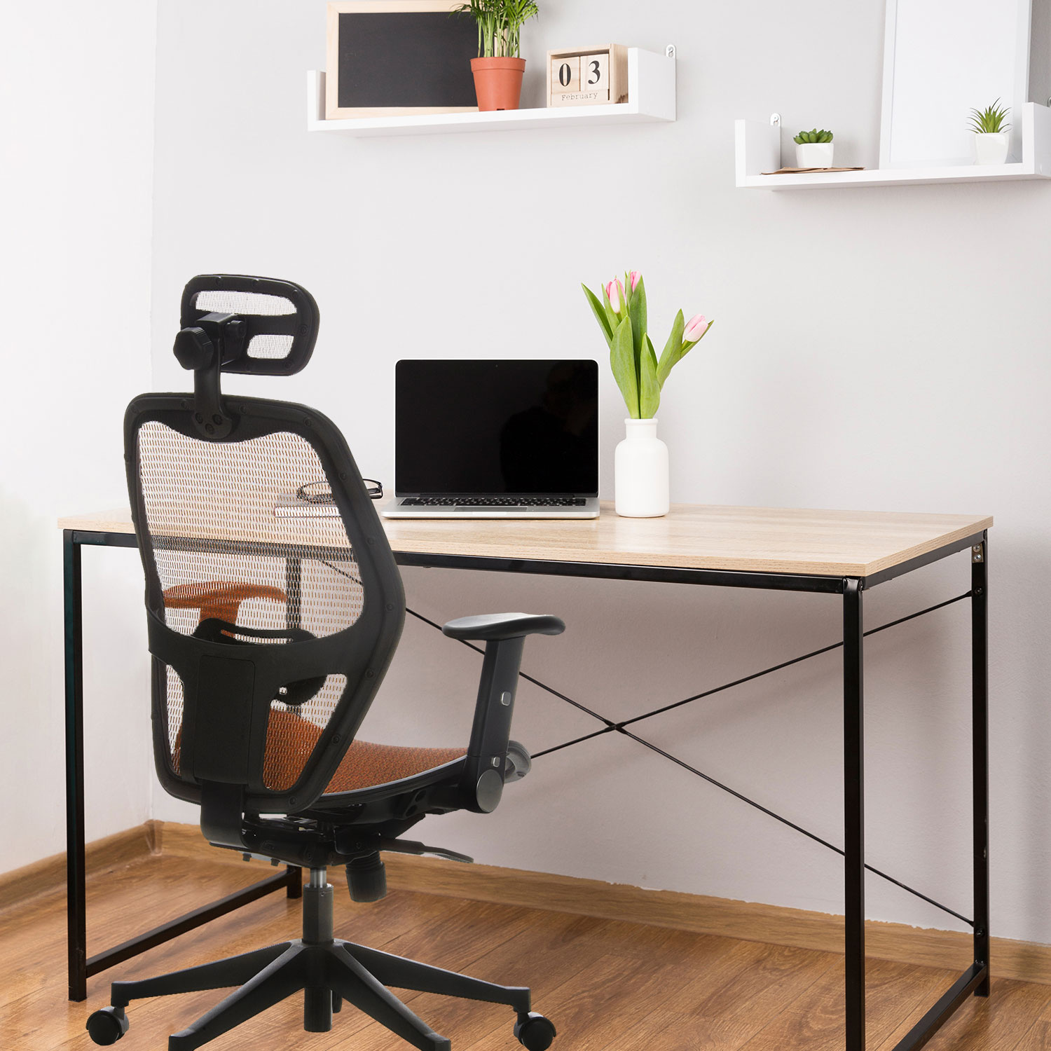 Ein Homeoffice mit Schreibtisch, schwarzem Stuhl, Laptop und Pflanzen auf Holzboden.