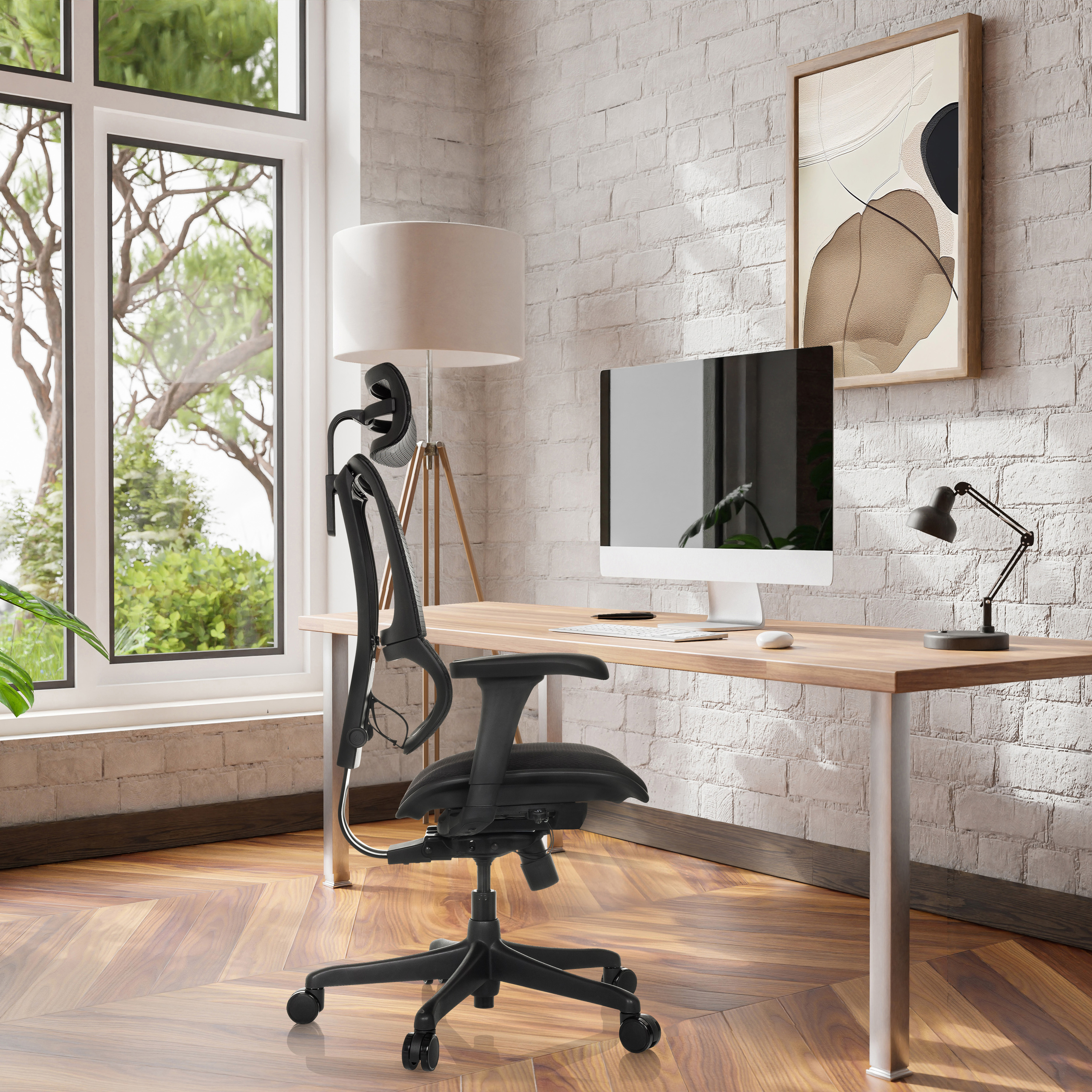 Schwarzer ergonomischer Bürostuhl in einem Büro mit Computer und Lampe auf dem Schreibtisch.
