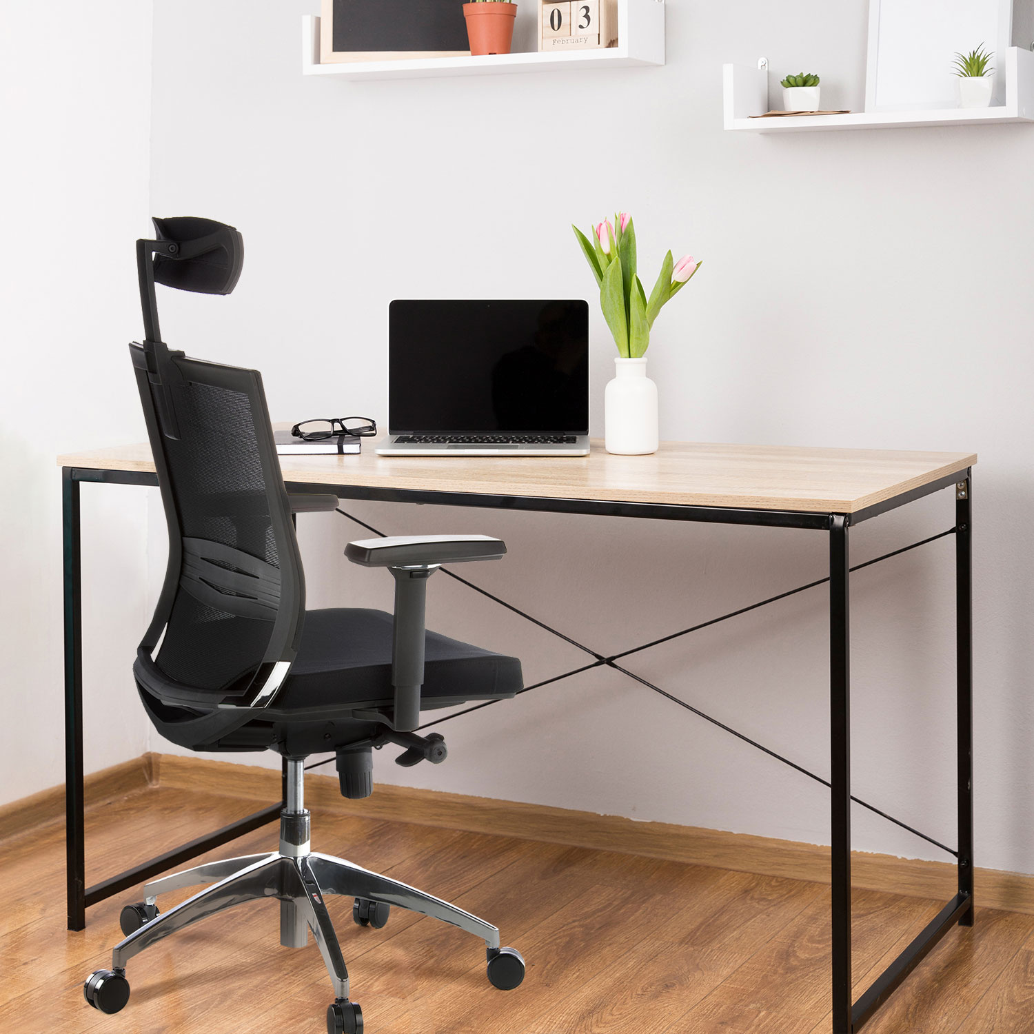 Schreibtisch-Setup mit schwarzem ergonomischem Stuhl, Laptop, Brille und einer Vase mit Blumen.
