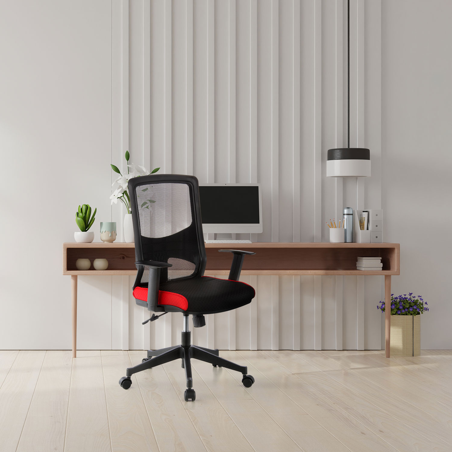 Schwarz-roter Stuhl in modernem Büro mit Schreibtisch, Computer, Pflanzen und Holzboden.