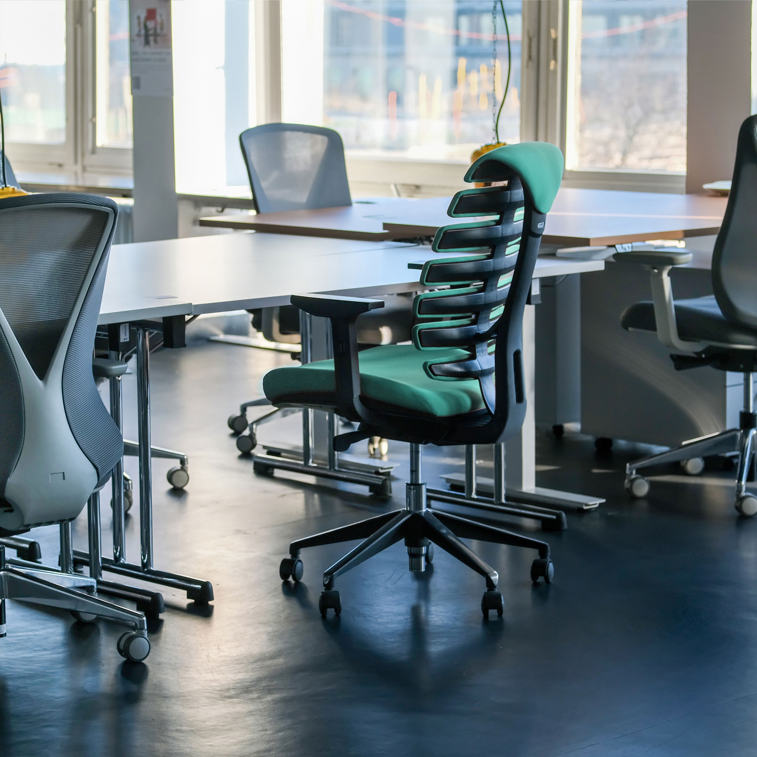 Büro mit mehreren Stühlen und Schreibtischen. Modernes Design, mit natürlichem Licht vom Fenster.