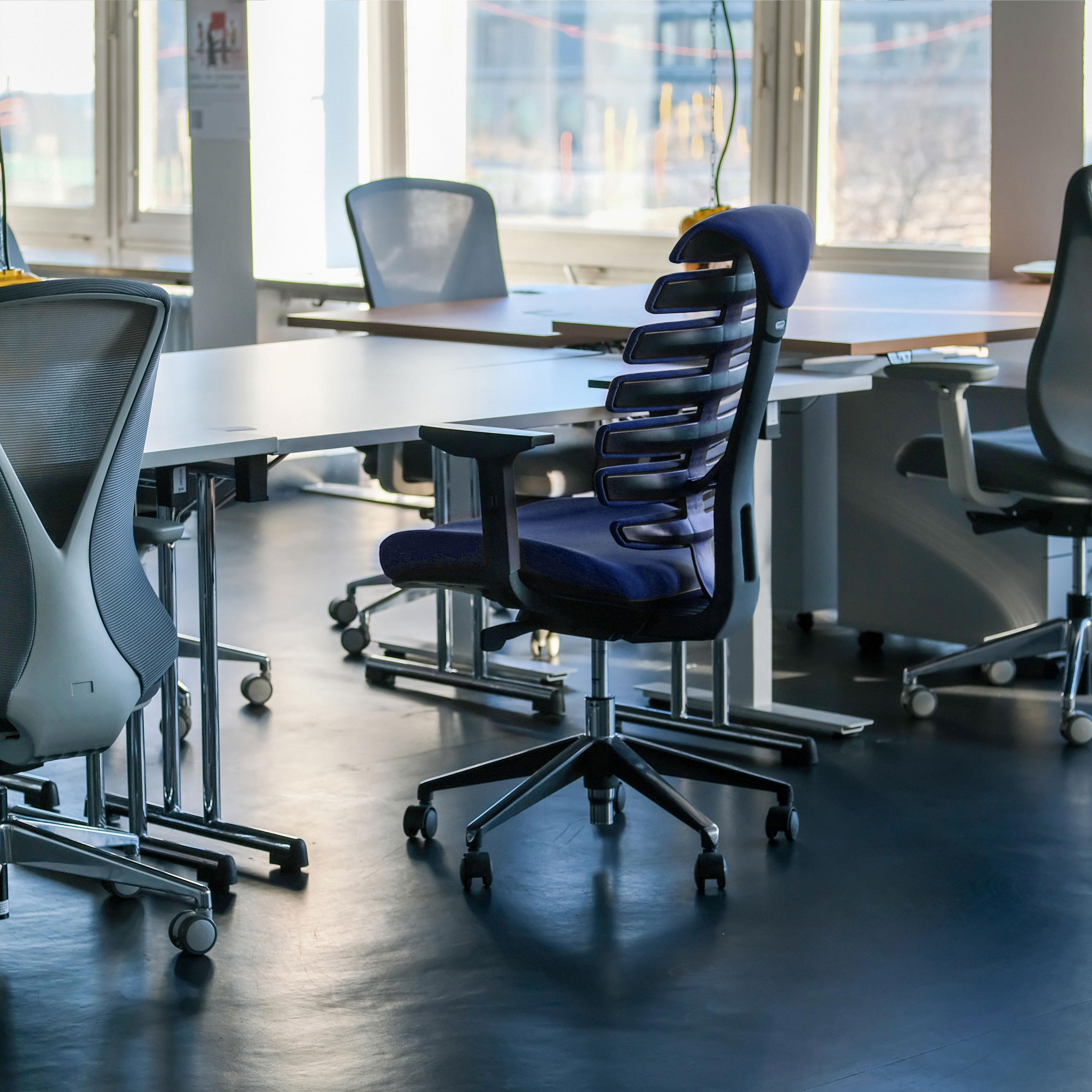 Ein Büro mit blauen Bürostühlen und großen Fenstern.