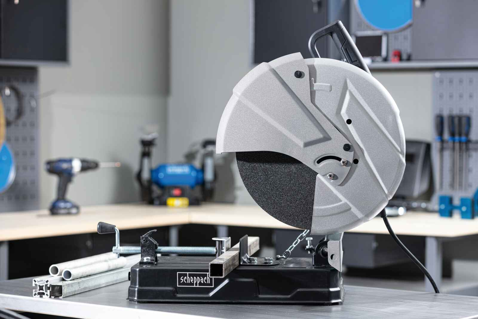 Metaalzaag met zwarte basis, zilveren mesbeschermer en metalen buis op de tafel.