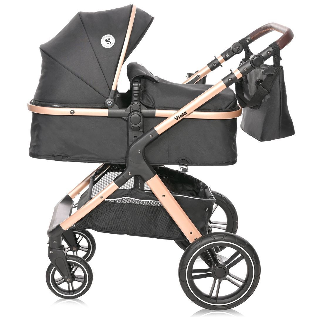 Schwarzer und roségoldfarbener Kinderwagen. Verfügt über ein Verdeck, einen Korb und eine Tasche. Räder sind schwarz und weiß.