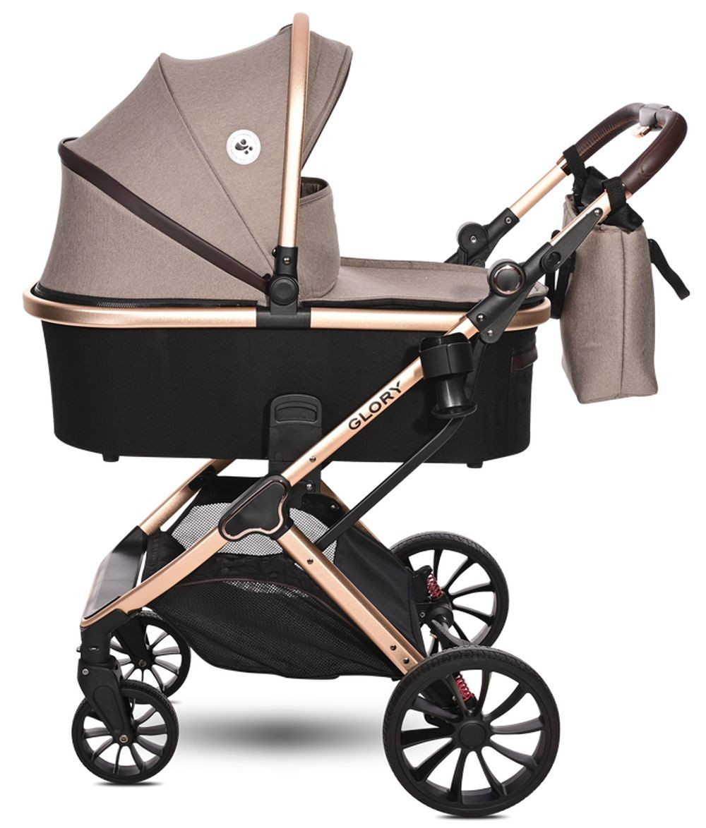 Un cochecito beige y negro con capazo. Tiene un marco de cobre y una bolsa.