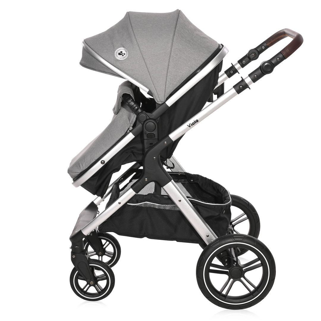 Grauer Kinderwagen mit schwarzen Akzenten. Seitenansicht, mit schwarzem Aufbewahrungskorb und Verdeck.