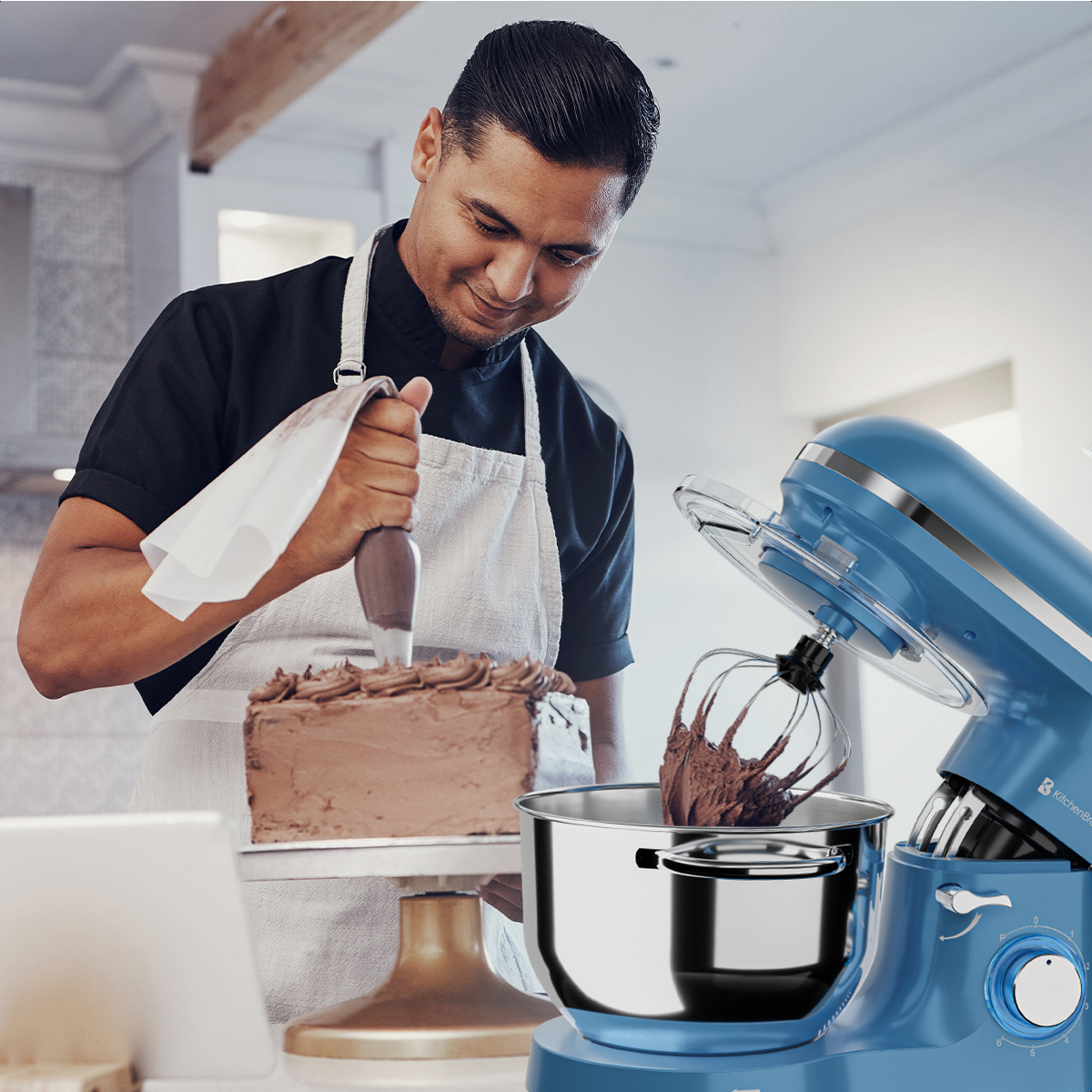 Een chef-kok snijdt een taart met chocolade glazuur, met behulp van een spatel. Een blauwe keukenmixer op de achtergrond.