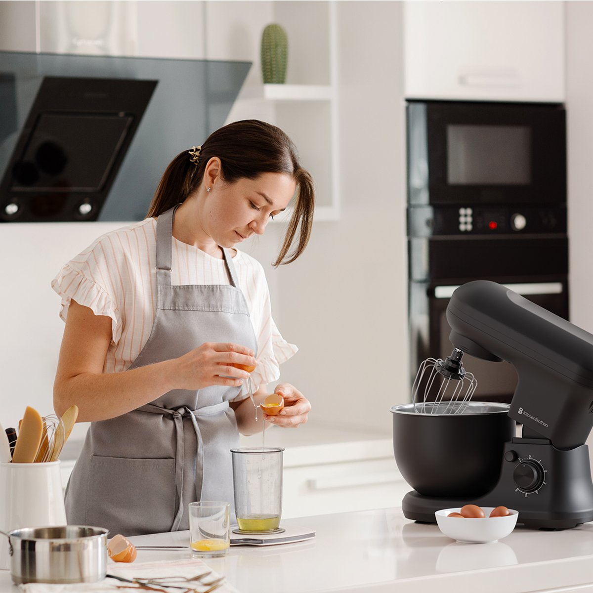 Vrouw die een ei in een maatbeker breekt, keukenscène met mixer en ingrediënten op het aanrecht.