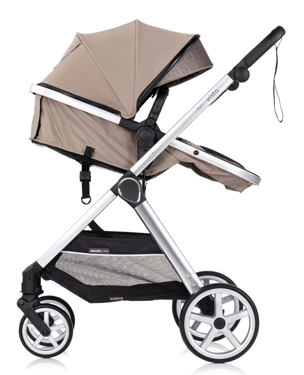 Beiger Kinderwagen mit silbernem Rahmen, schwarzem Korb und vier Rädern. Mit Sonnenschutz.
