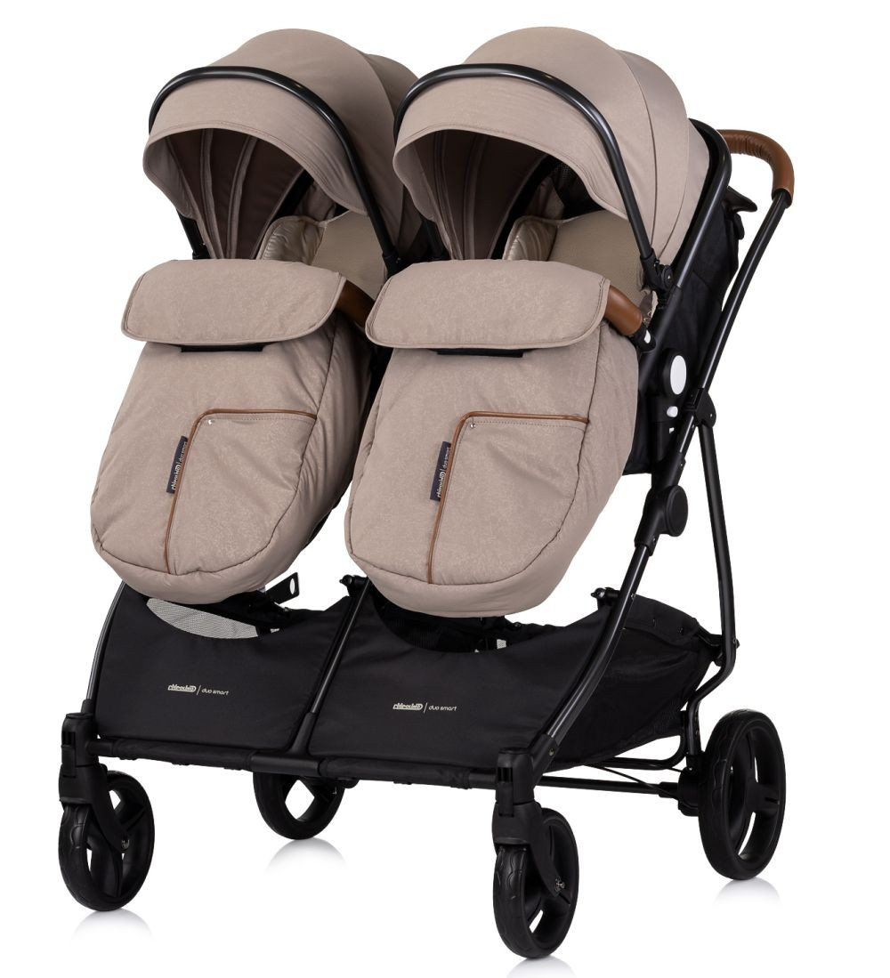 Doppelkinderwagen mit beigem Verdeck und schwarzem Rahmen, zwei Sitze.