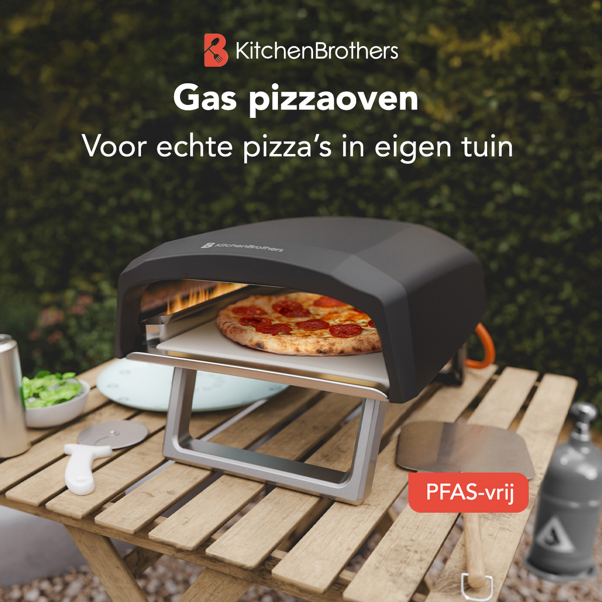 Black pizza oven on wooden table. Pizza inside on stone. Greenery and gas tank in background.
